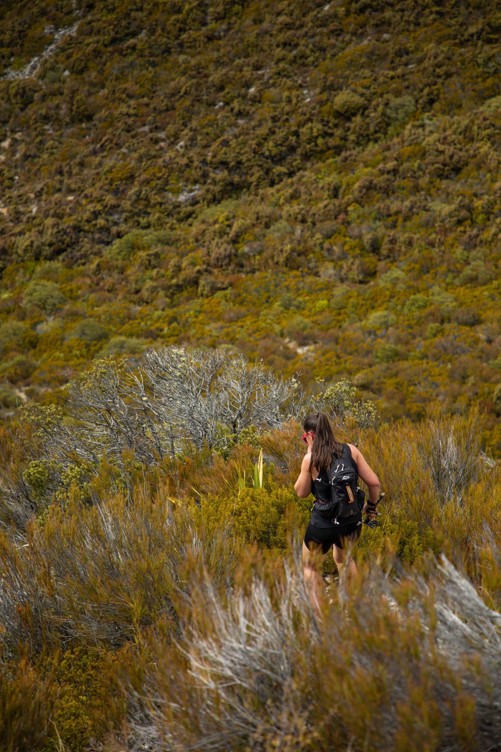 A woman with a backpack is hiking up a hill.
