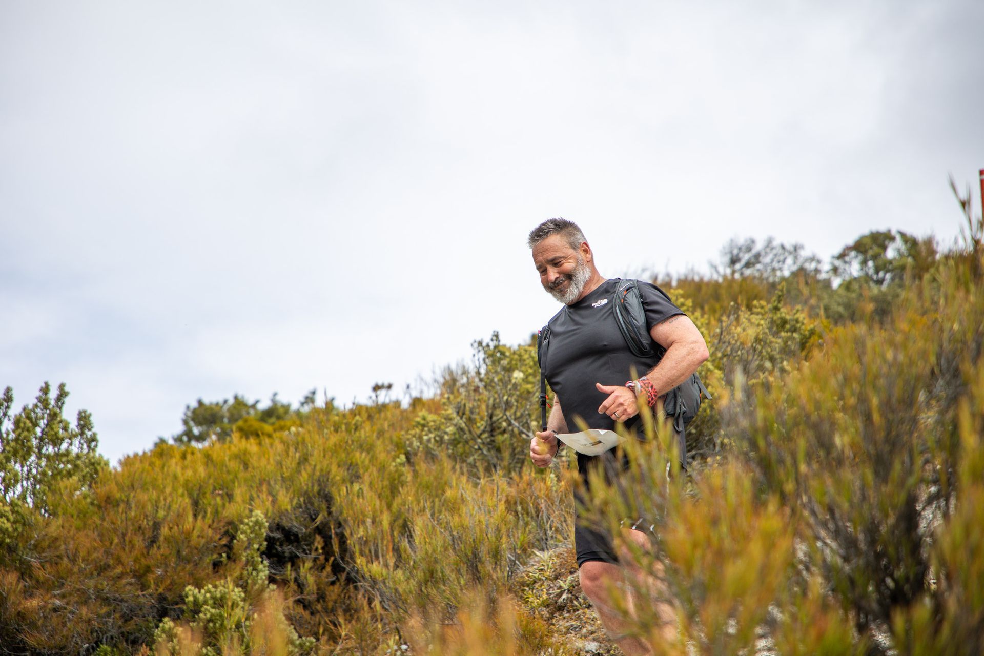 A man is walking through a field of tall grass.