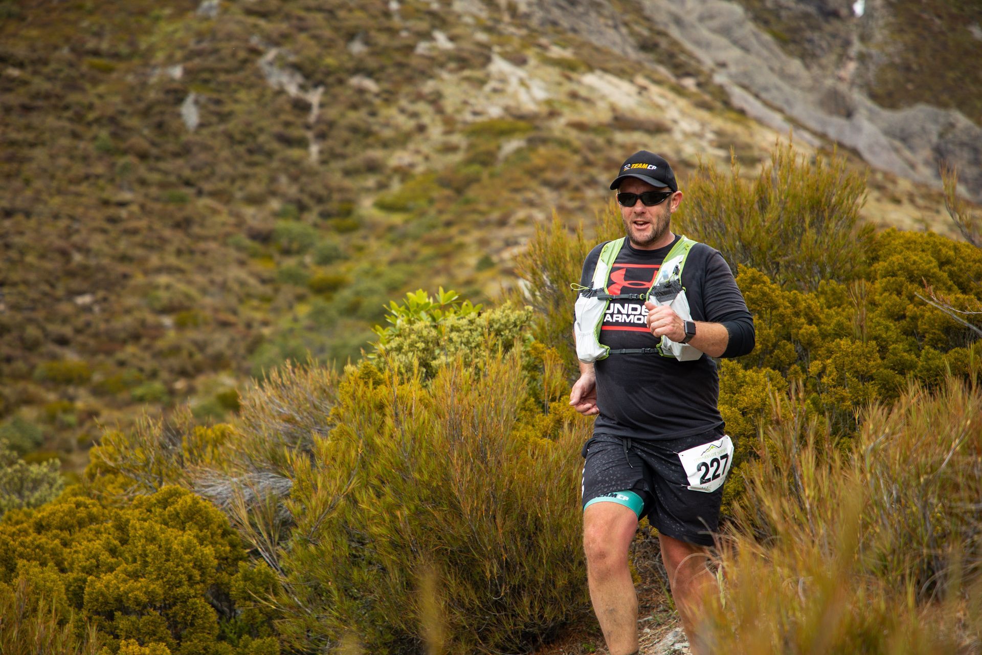 A man is running on a trail in the mountains.