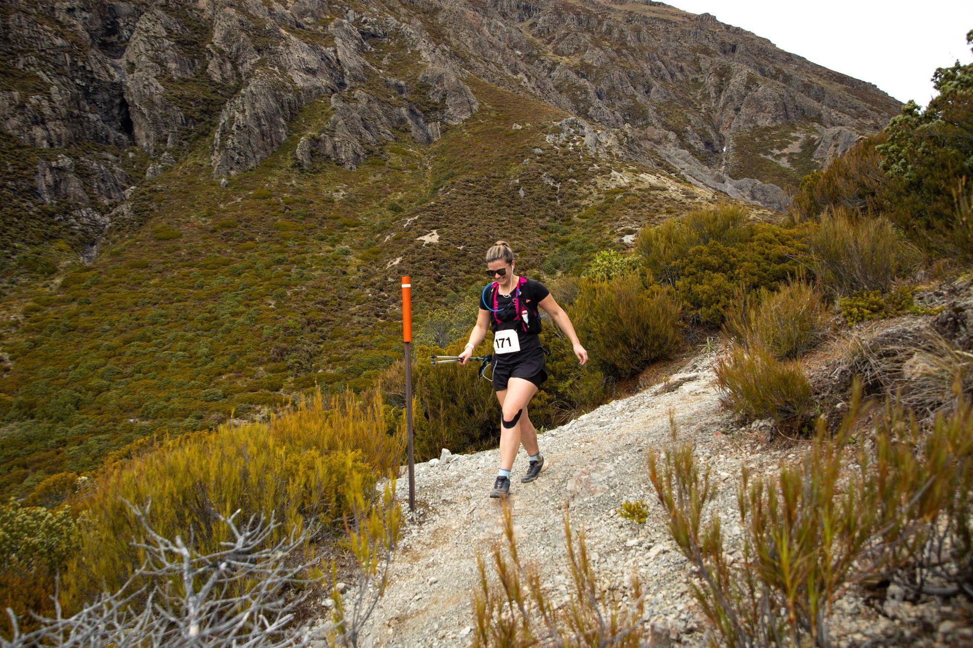 A woman is running down a dirt path in the mountains.