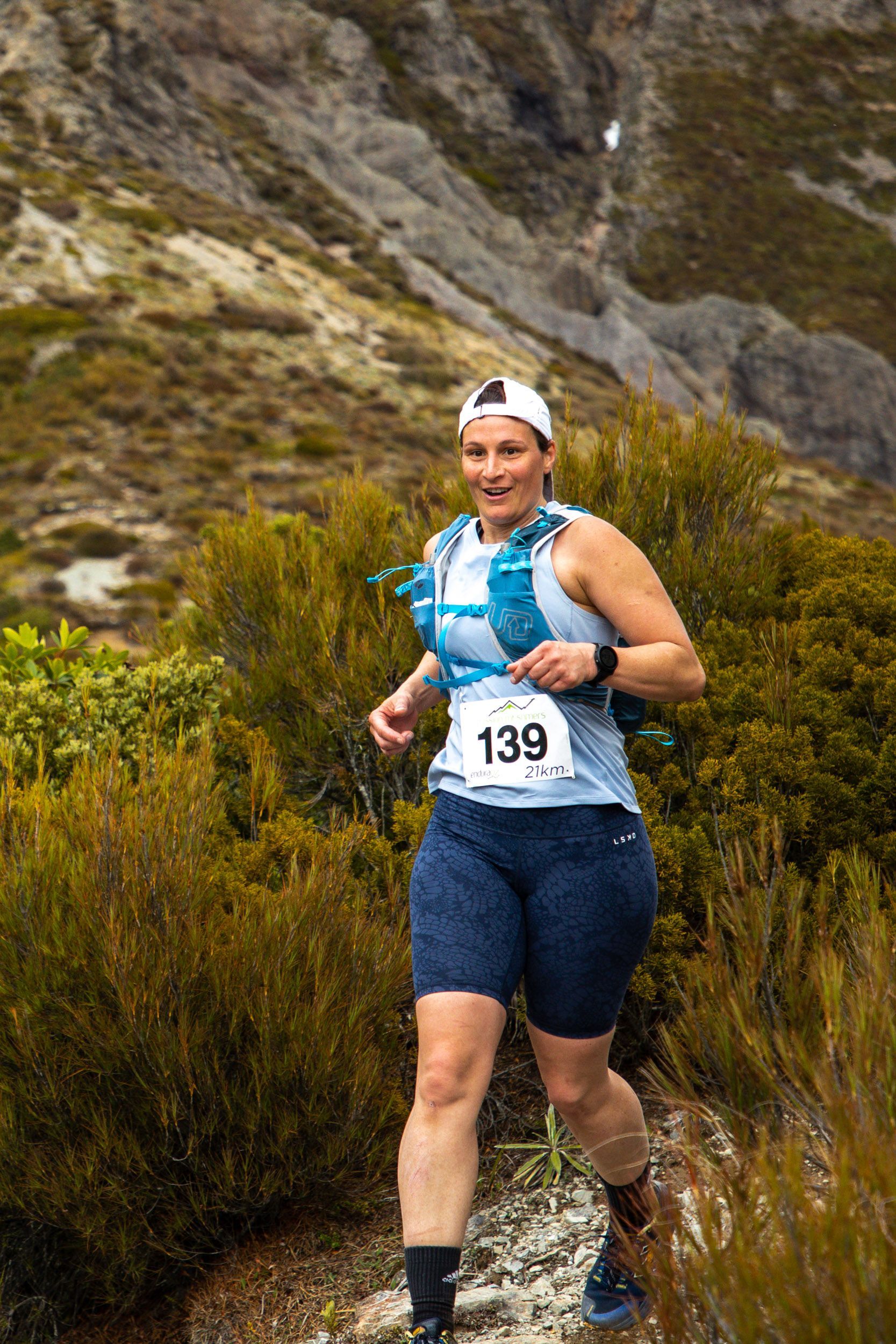 A woman is running on a trail in the mountains.