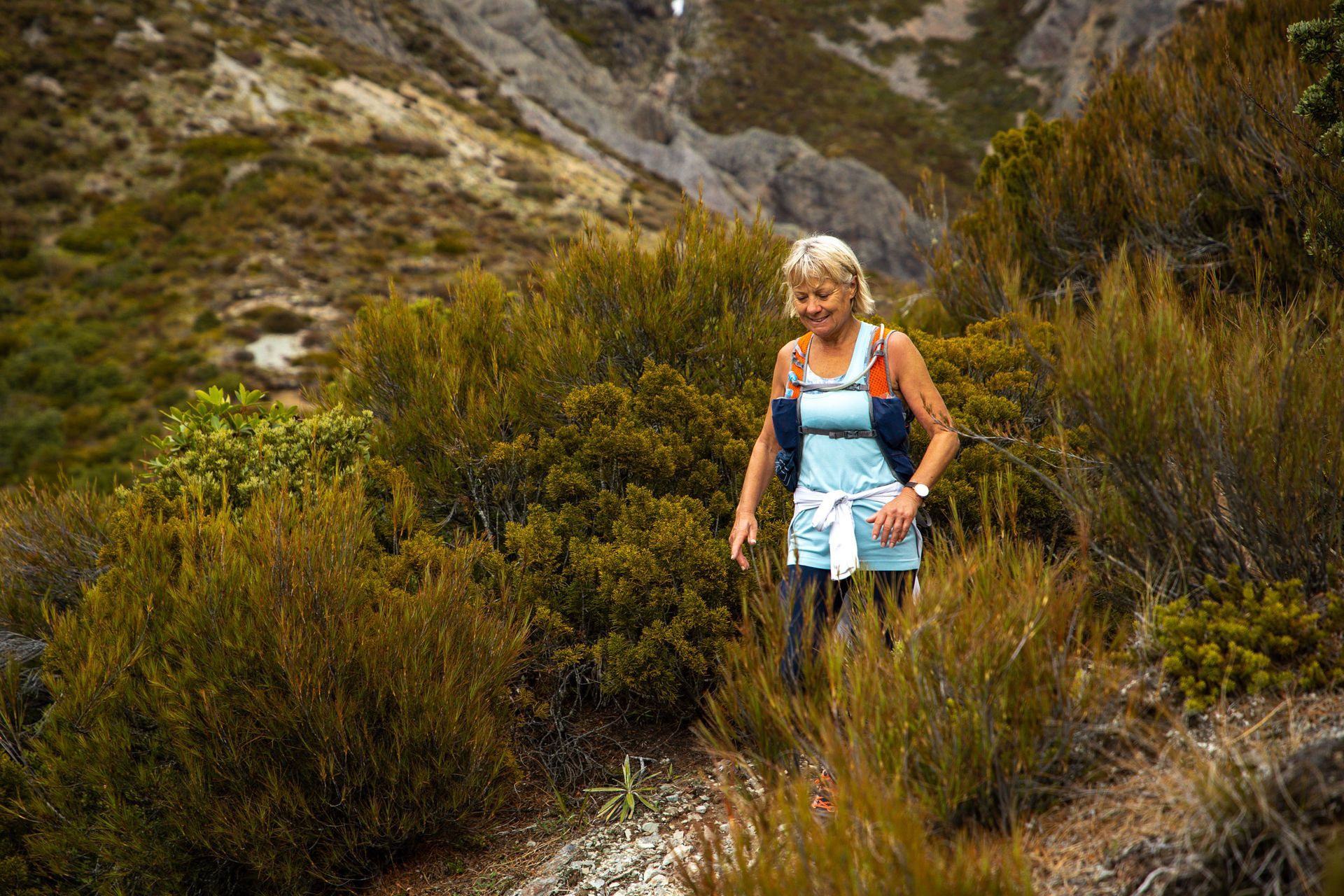 A woman is walking on a trail in the woods.
