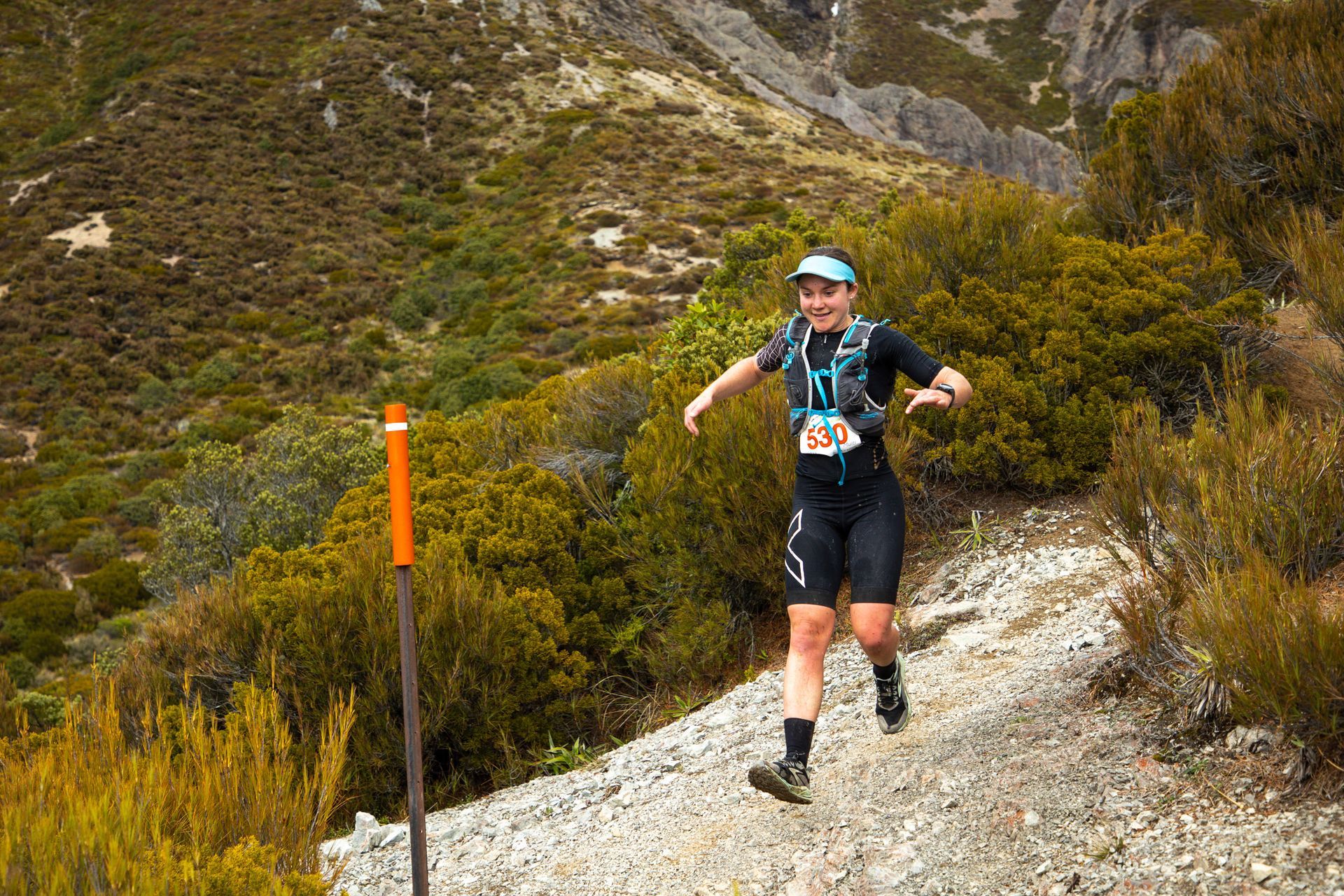 A man is running on a trail in the mountains.