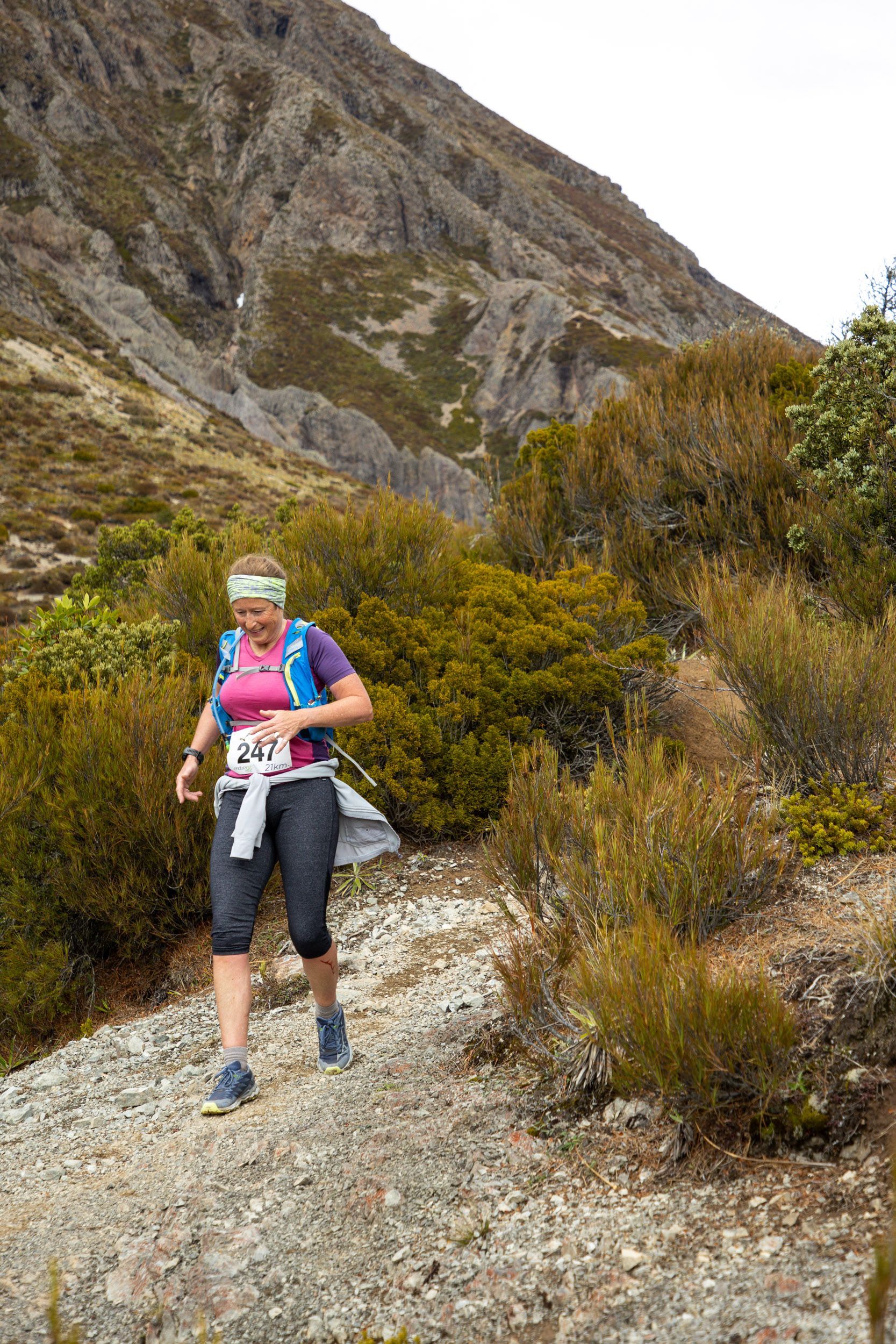 A woman is walking down a dirt path in the mountains.
