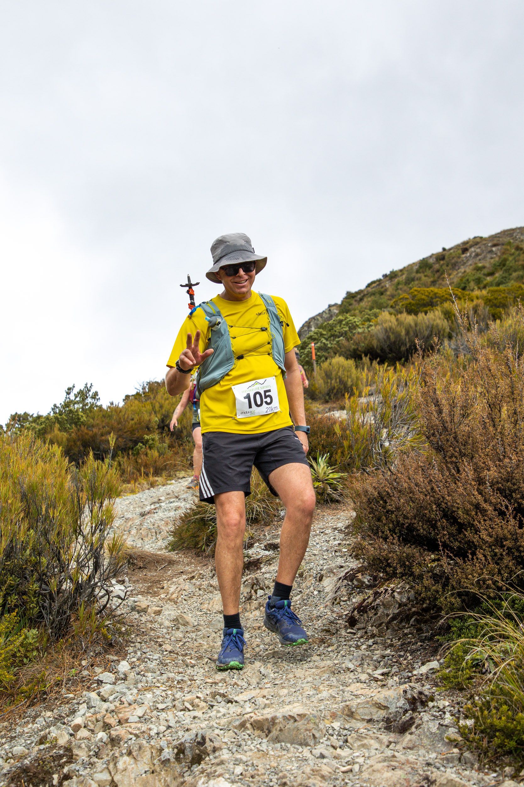 A man is walking up a dirt path in the mountains.