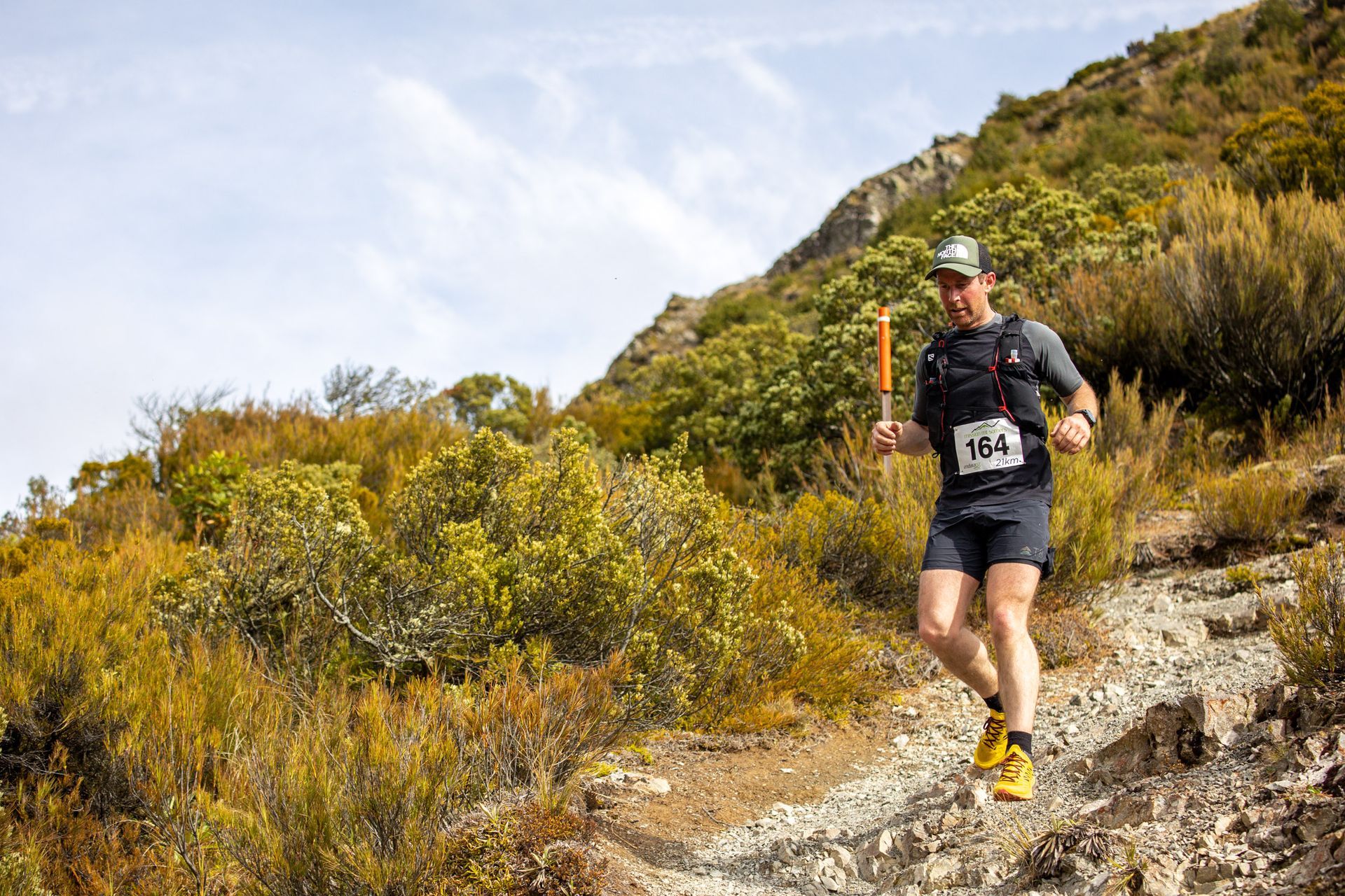 A man is running on a trail in the woods.