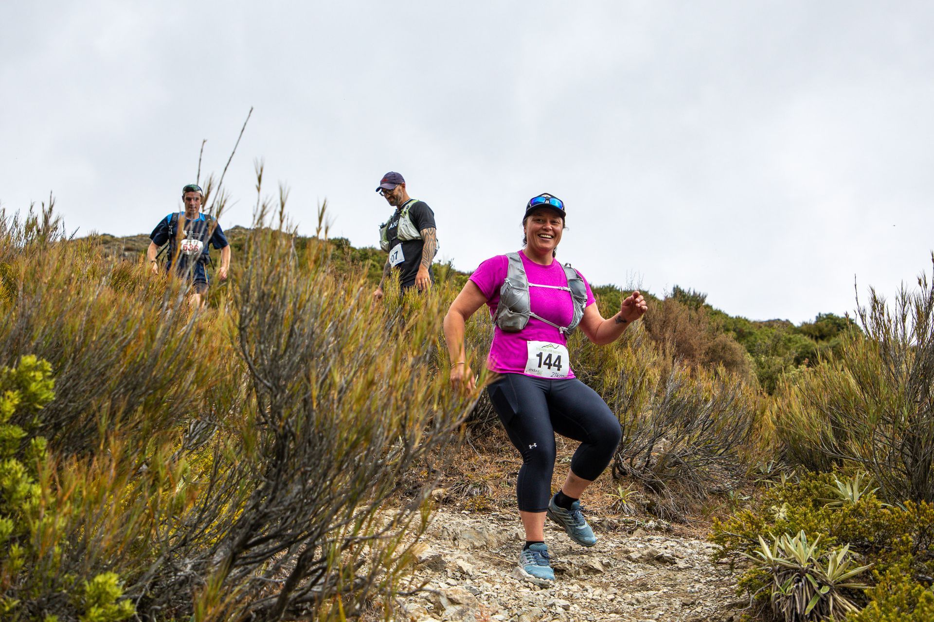 A group of people are running on a trail in the woods.