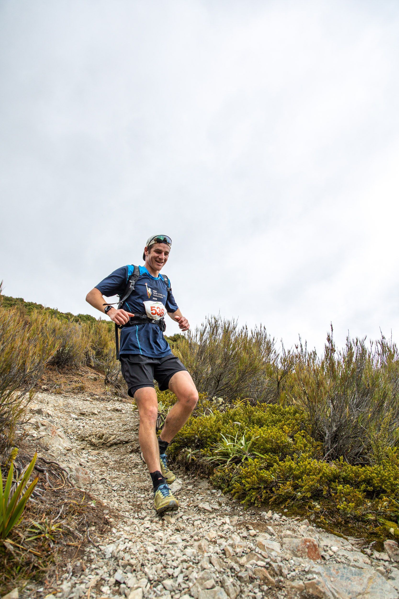 A man is running up a rocky hill on a trail.