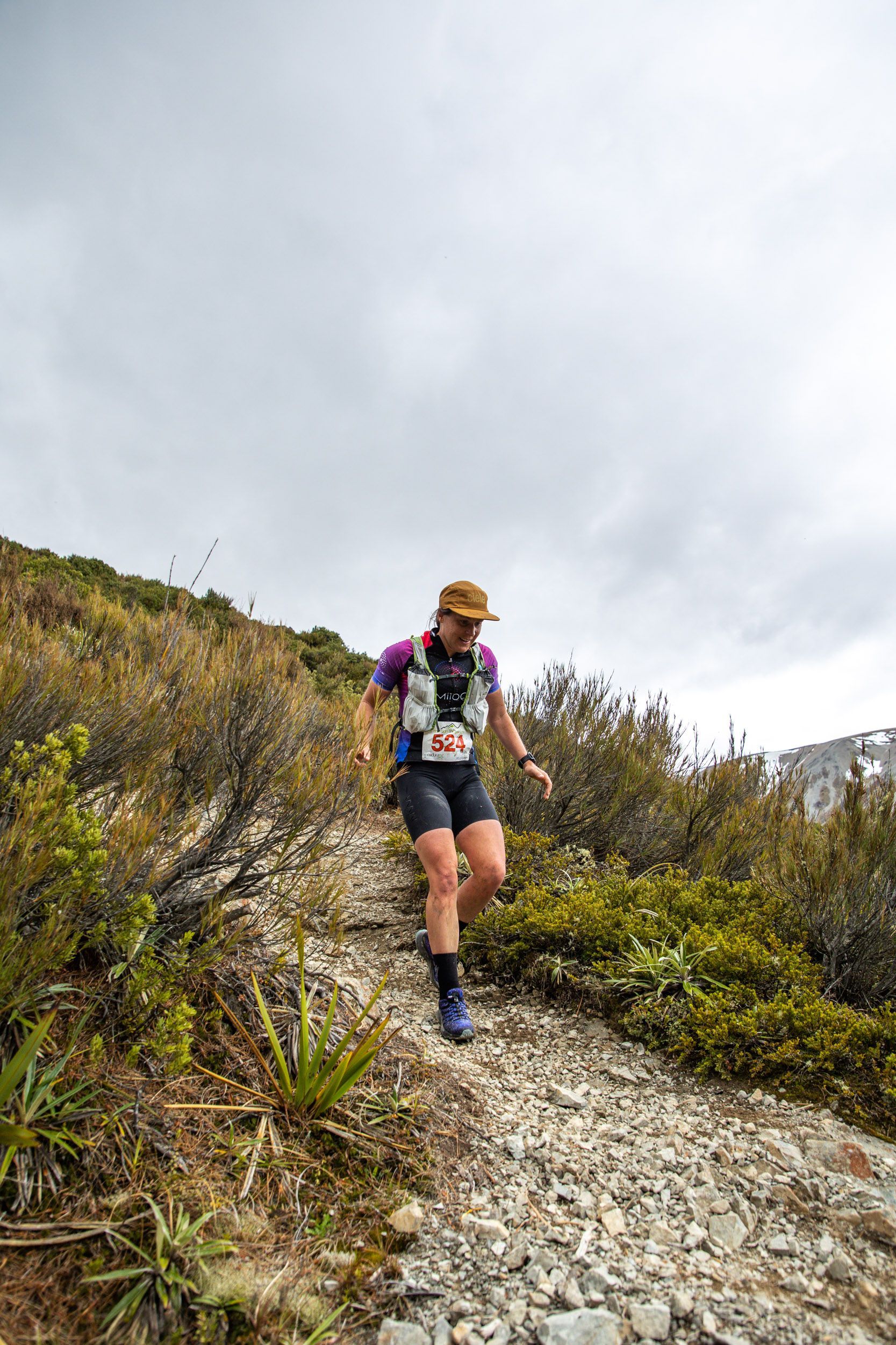 A man is running down a rocky trail in the mountains.