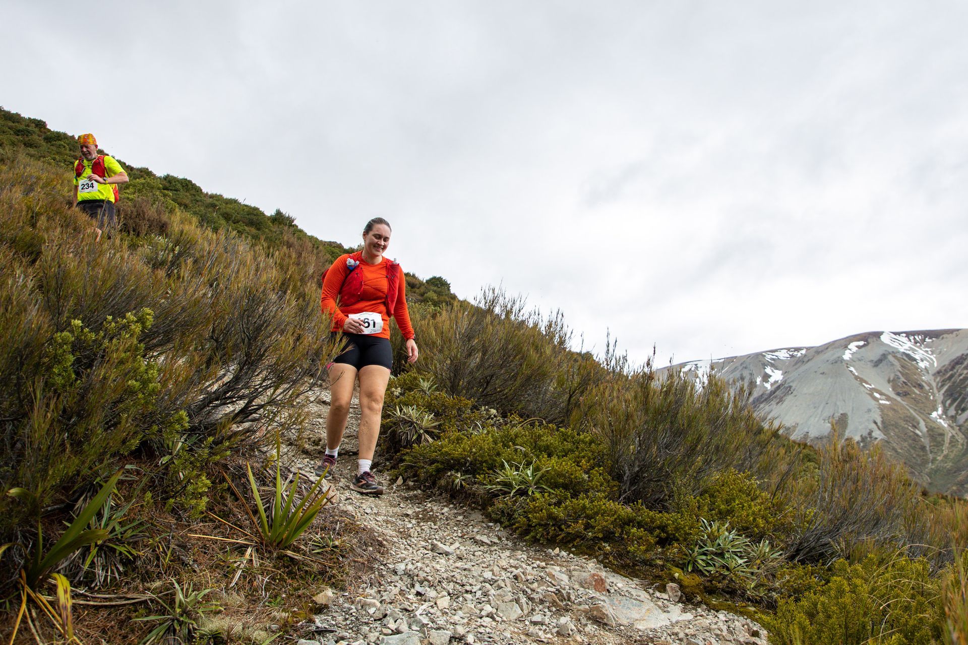 A woman is walking up a hill on a trail.