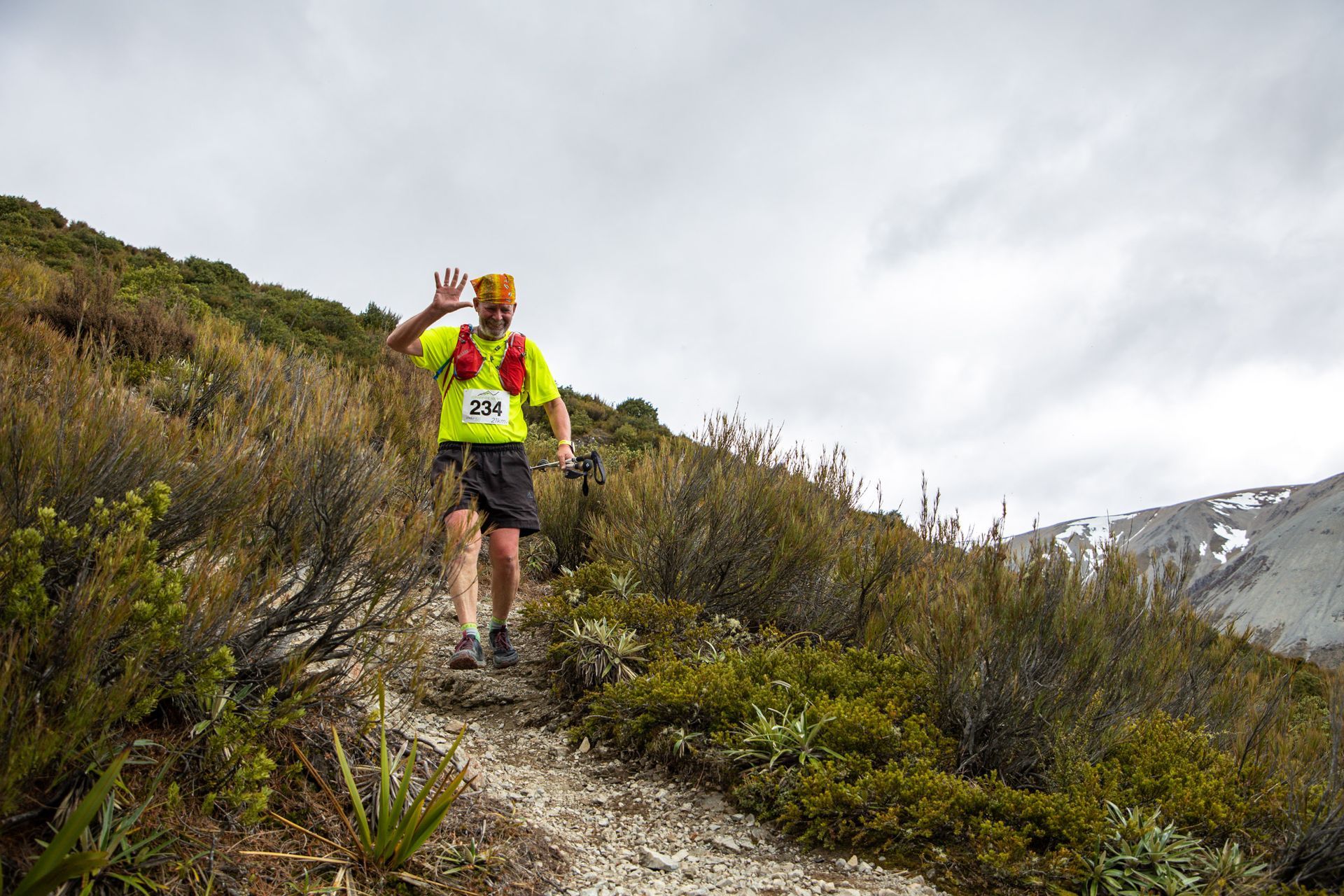 A man is walking down a dirt path in the woods.