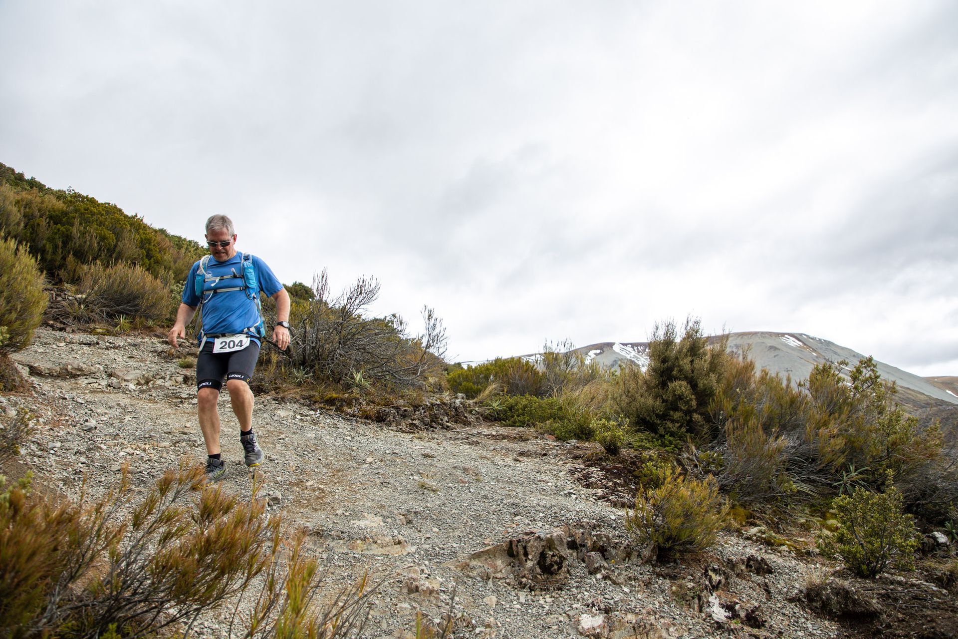 A man is running on a dirt road in the mountains.
