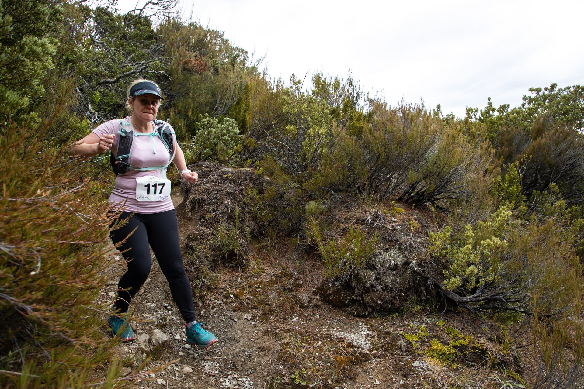 A woman is running on a trail in the woods.