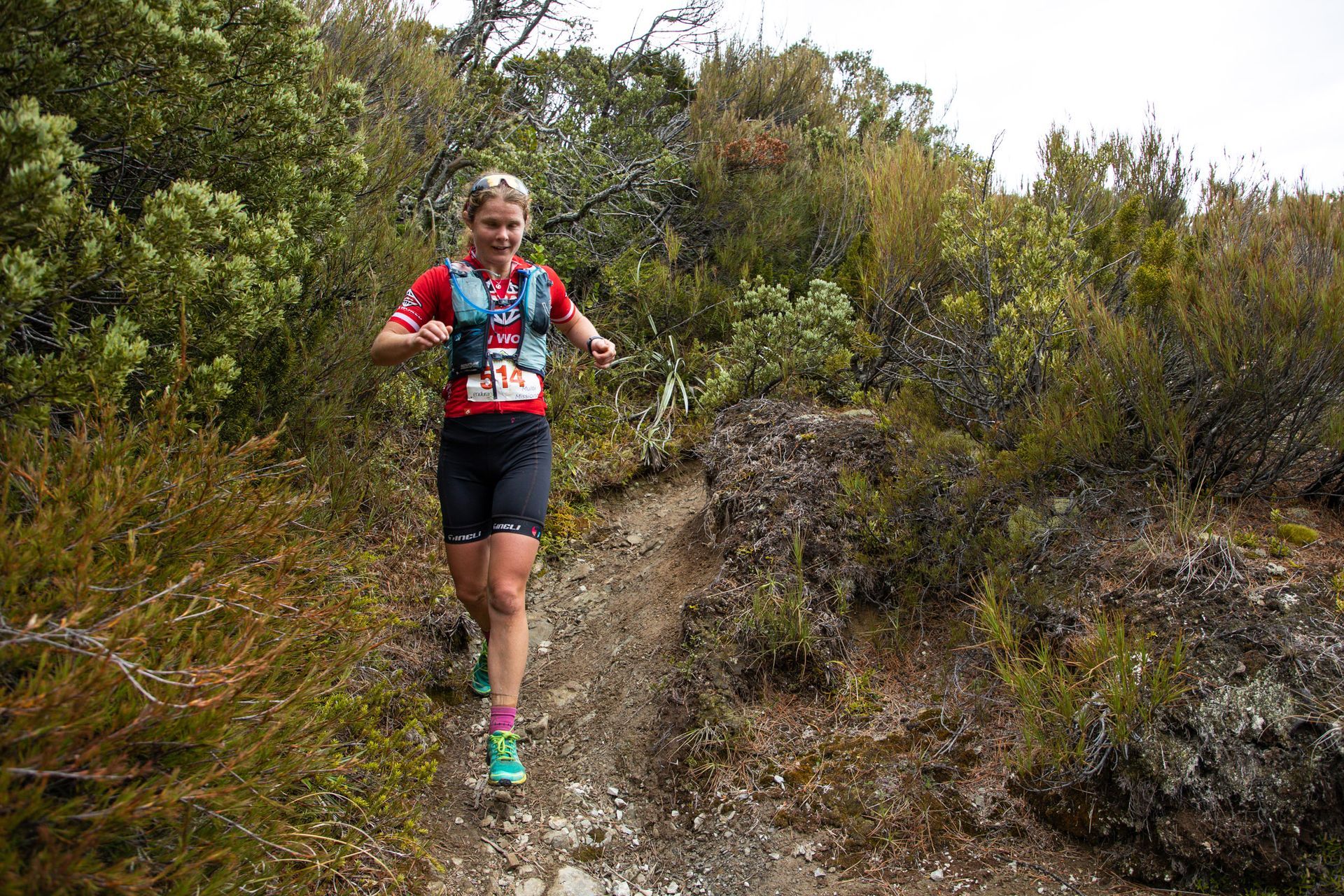 A woman is running on a trail in the woods.