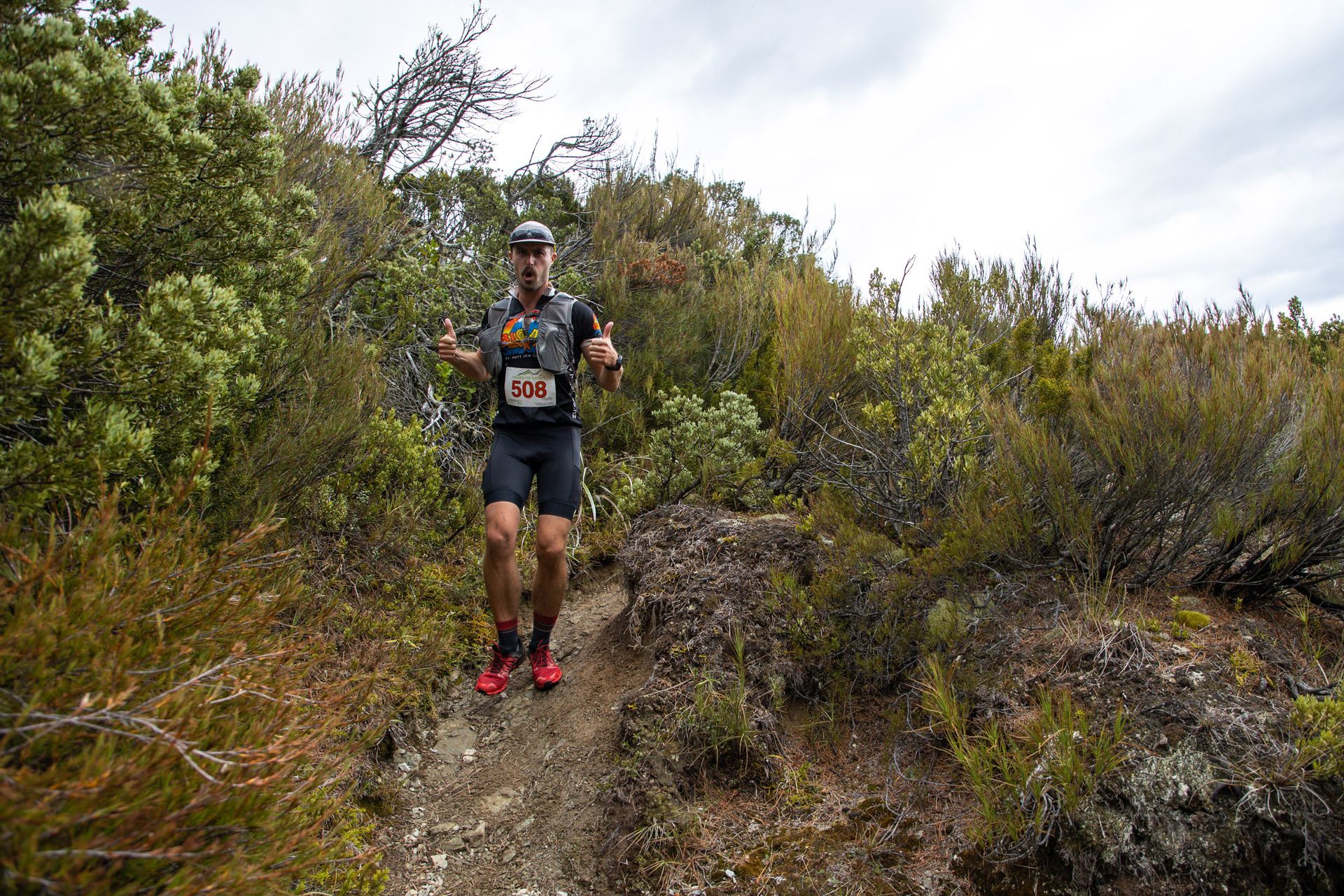 A man is running on a trail in the woods.