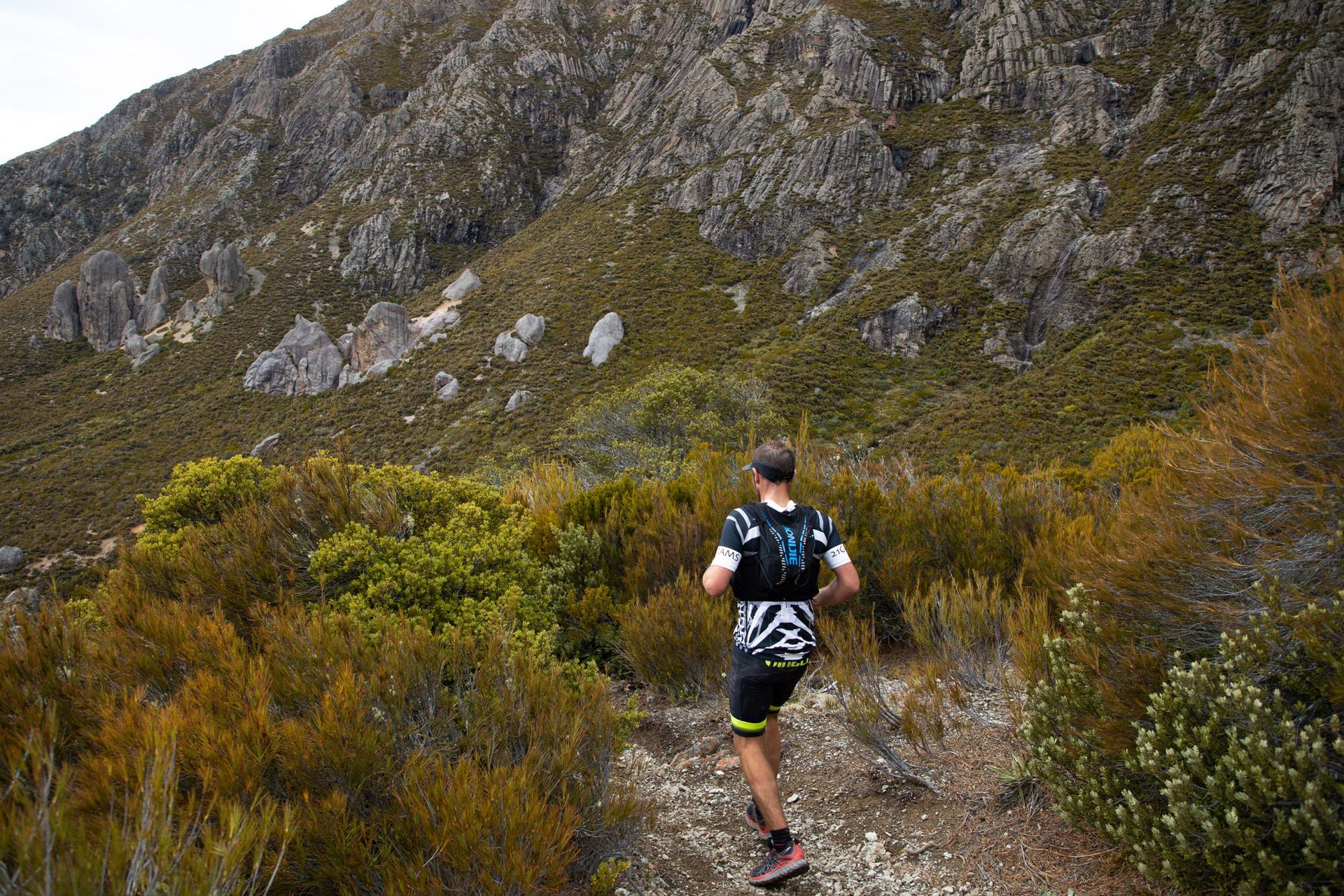 A man is running on a trail in the mountains.