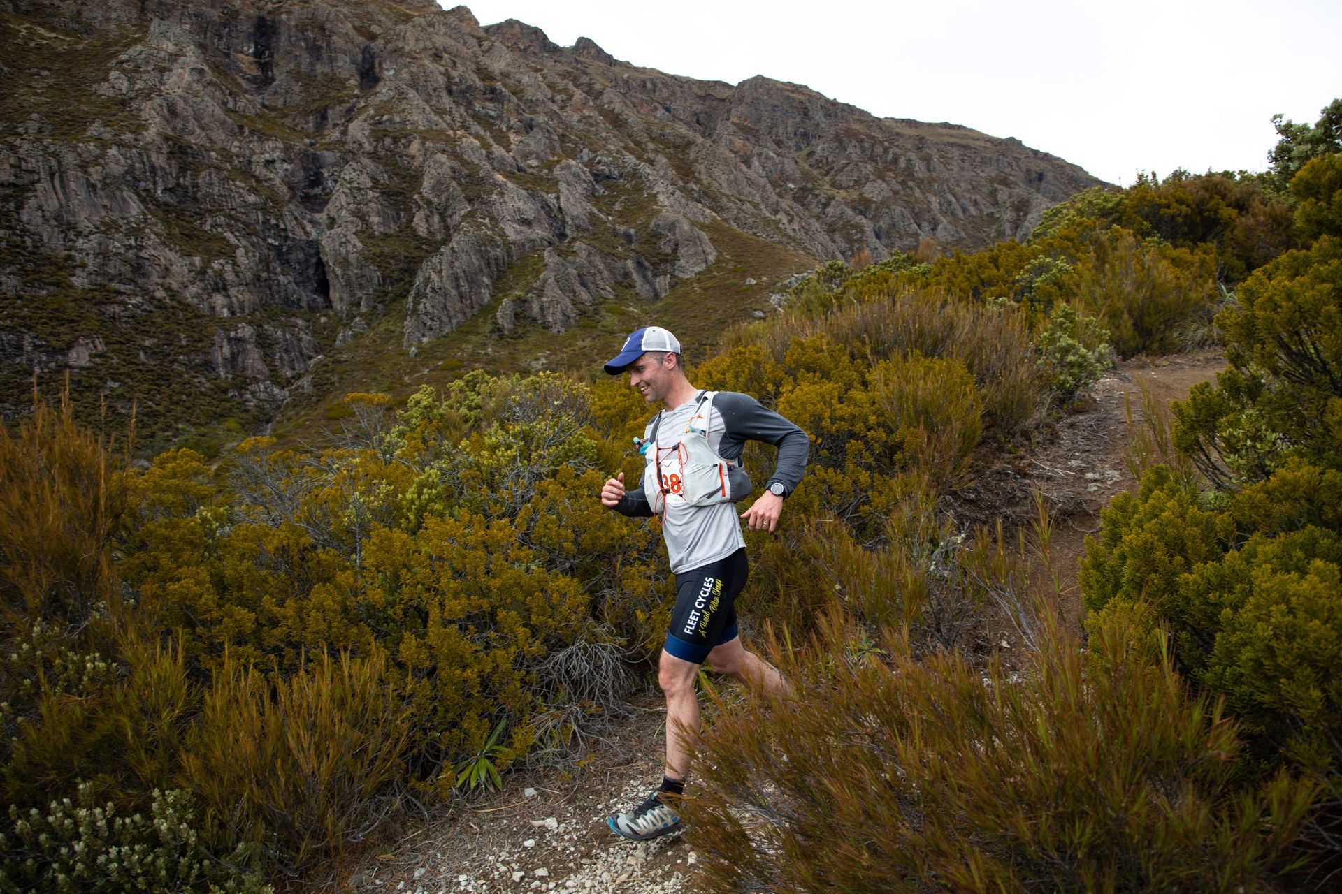 A man is running on a trail in the mountains.
