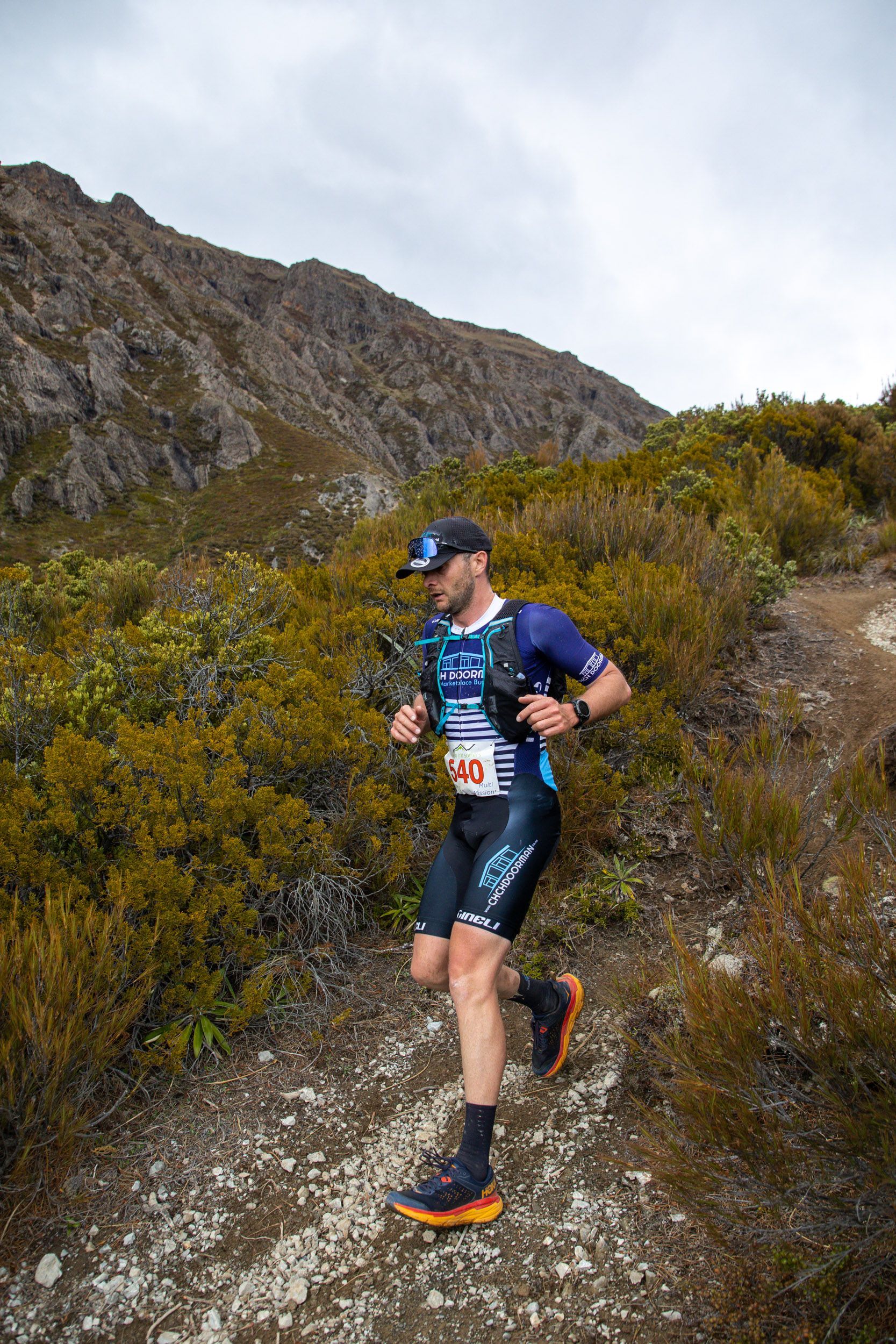 A man is running on a trail in the mountains.
