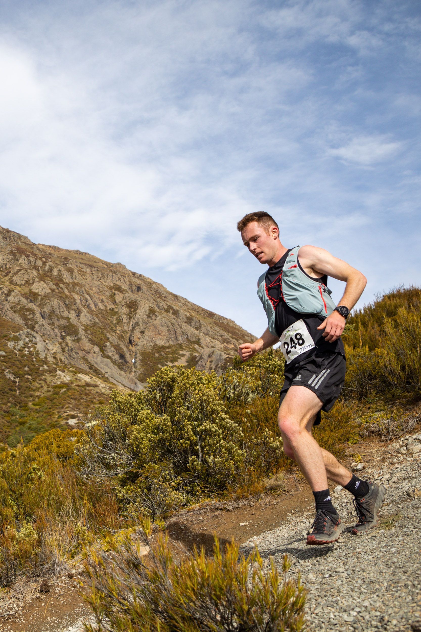 A man is running on a trail in the mountains.