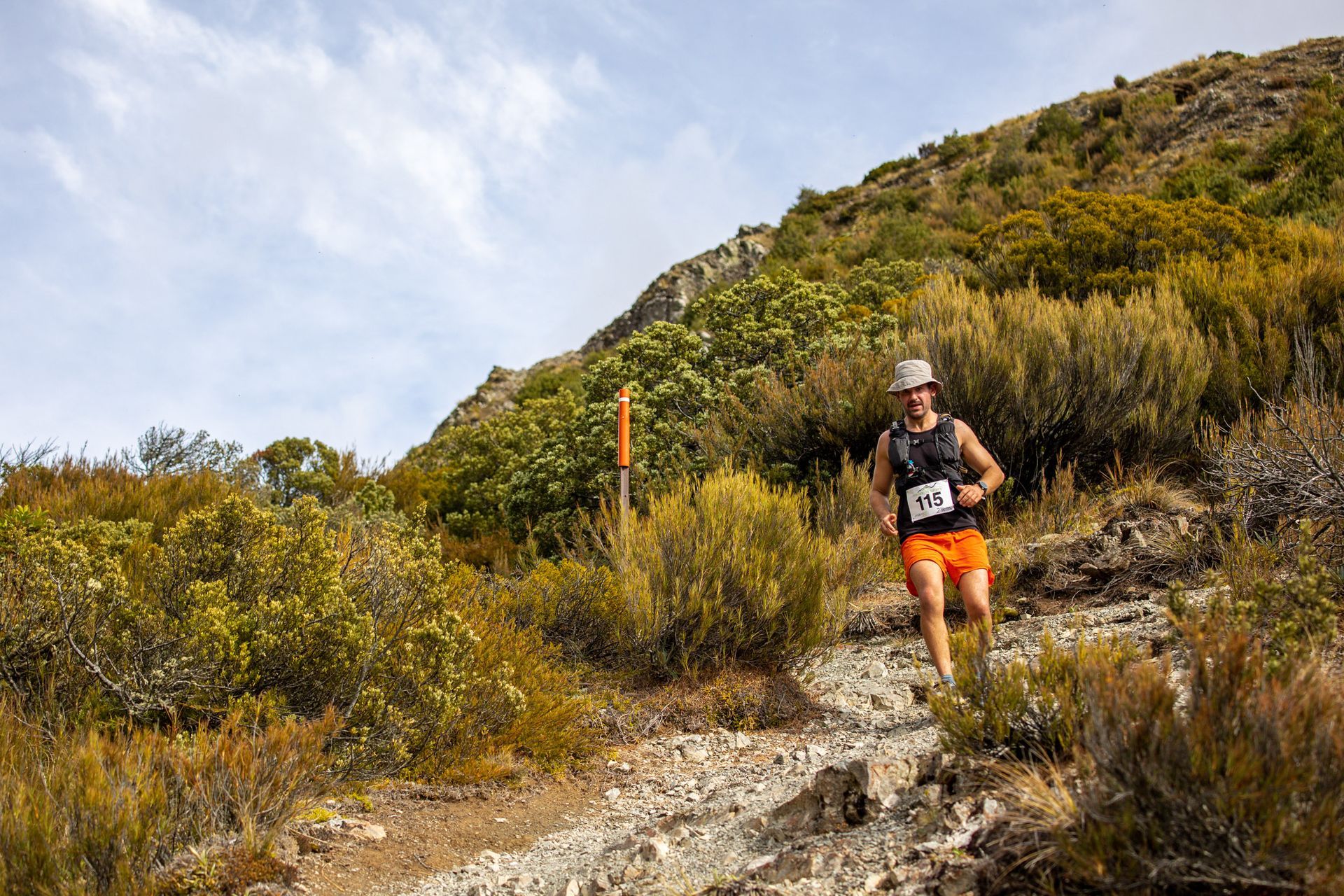 A man is running up a hill on a trail.