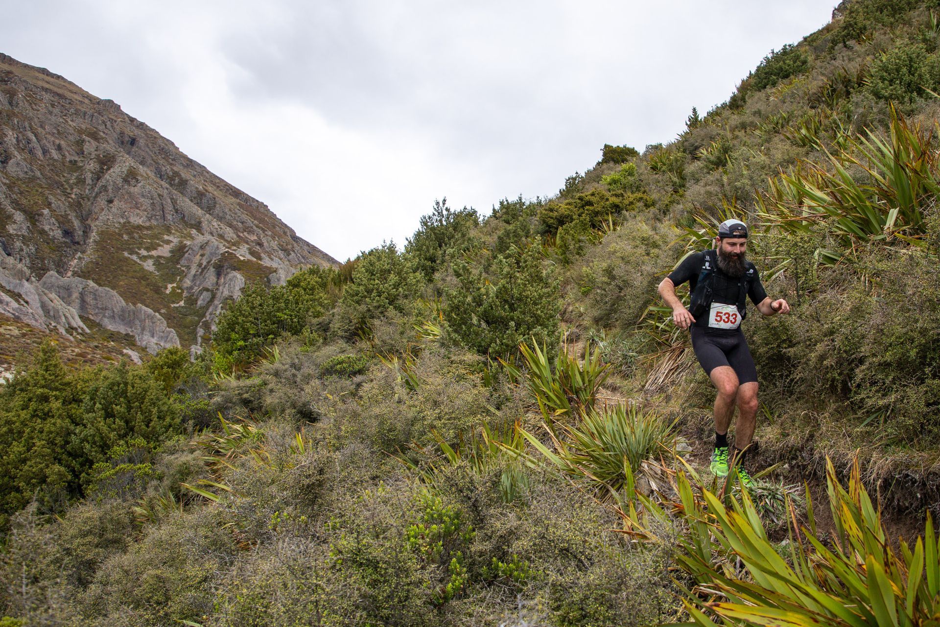 A man is running up a hill in the woods.