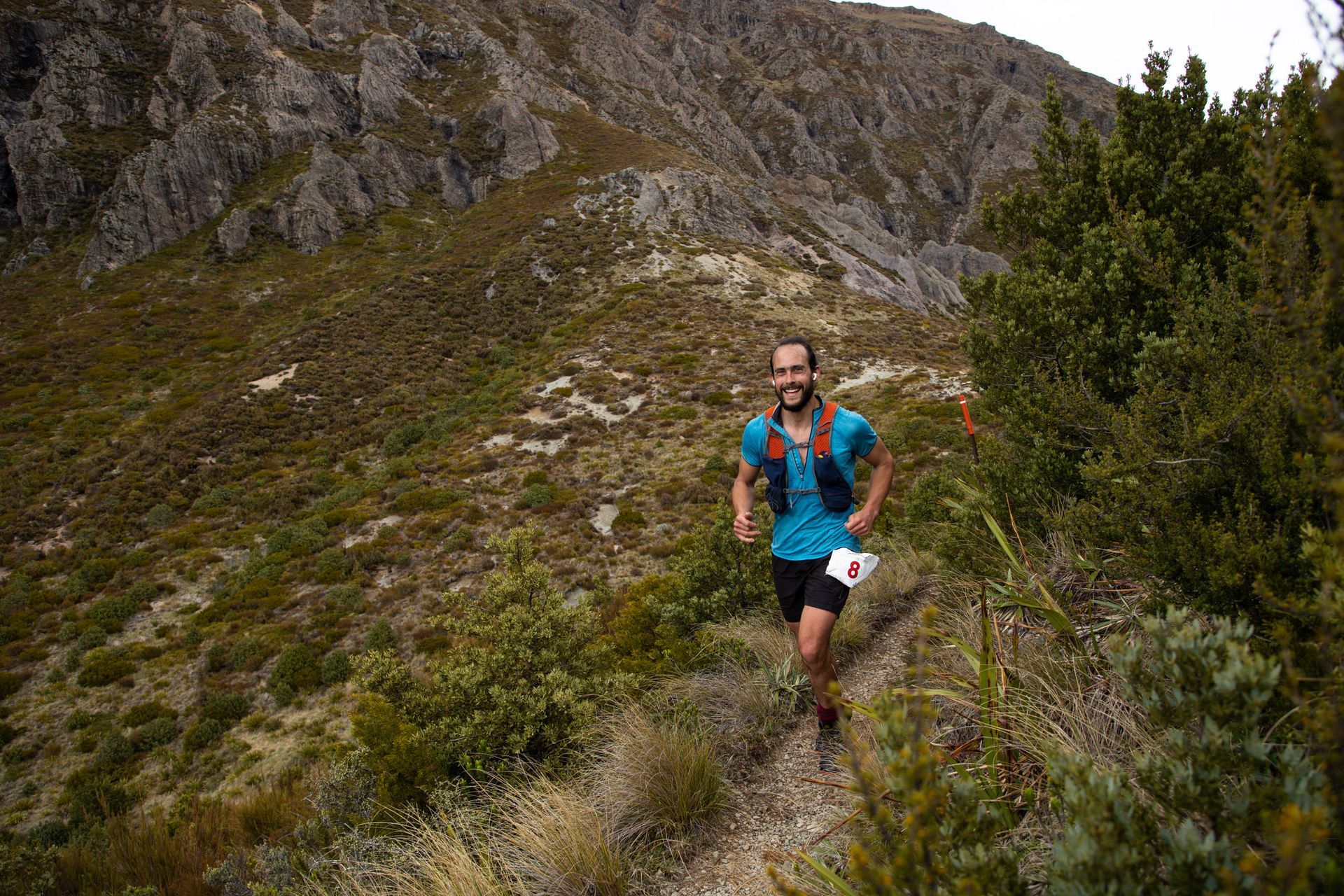 A man is running on a trail in the mountains.