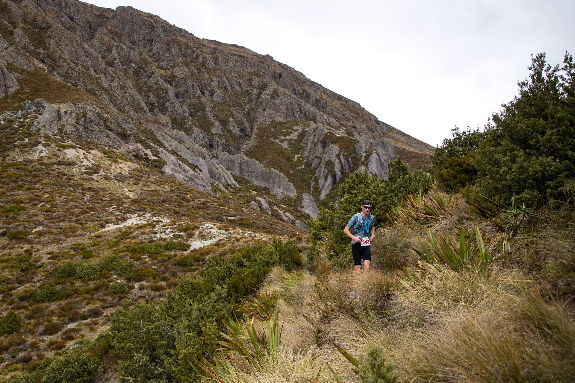 A man is running on a trail in the mountains.