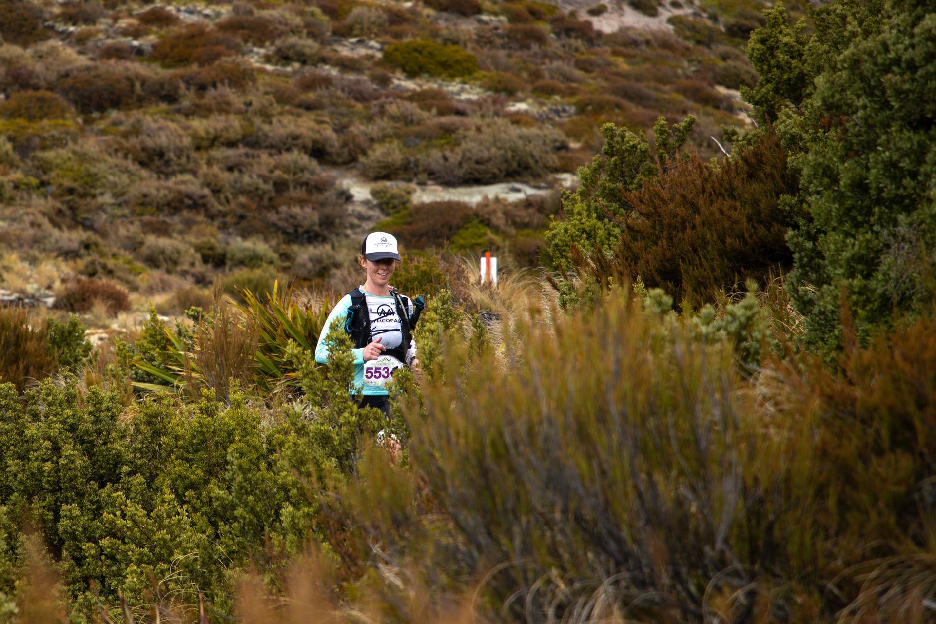 A man is running through a lush green field.