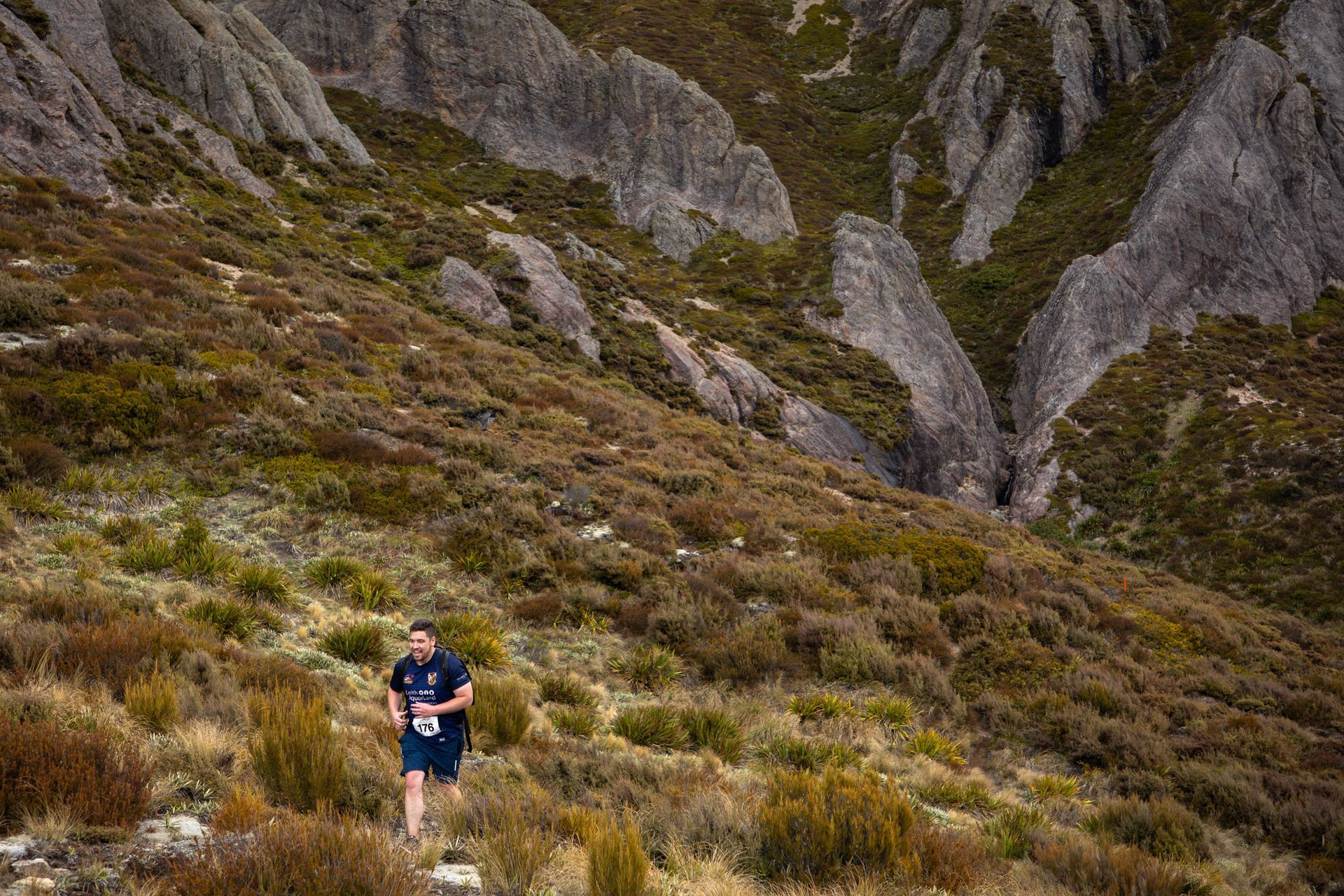 A man is running down a hill in the mountains.