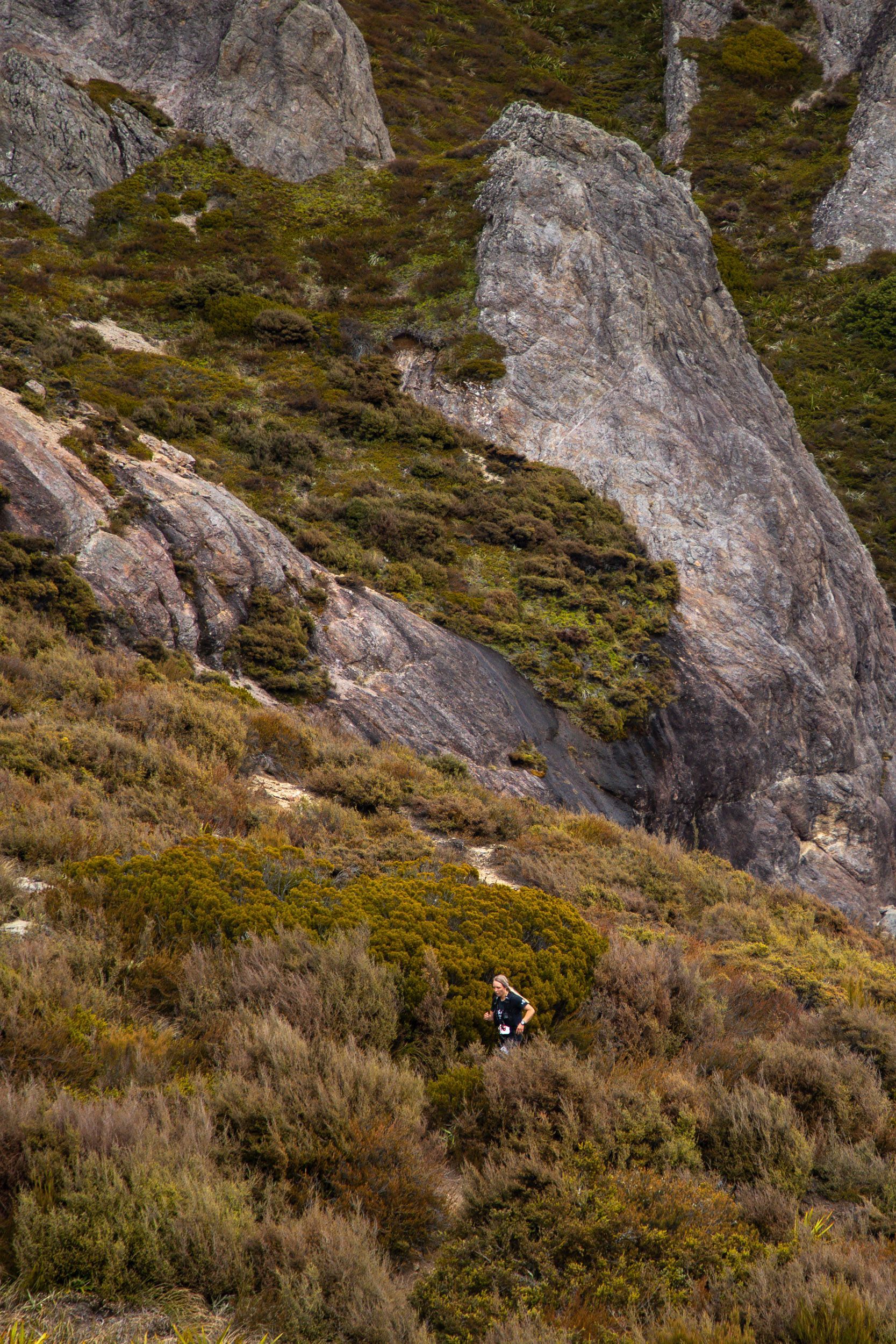 A person is sitting on a rock in the middle of a mountain.