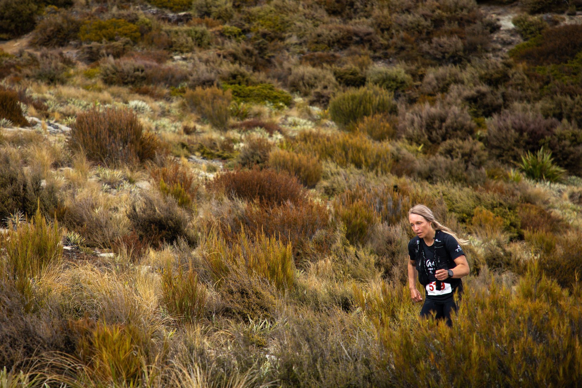 A woman is running down a hill in the woods.