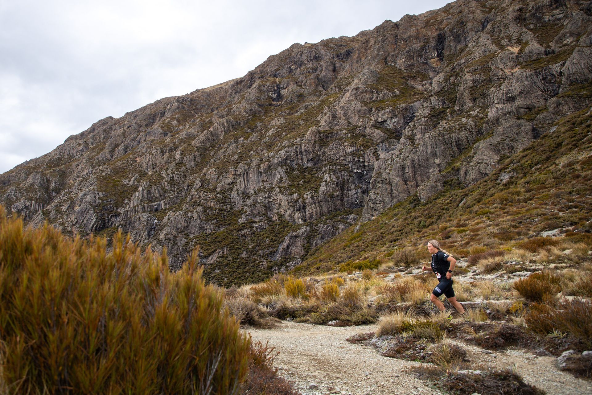 A person is running down a dirt path in the mountains.