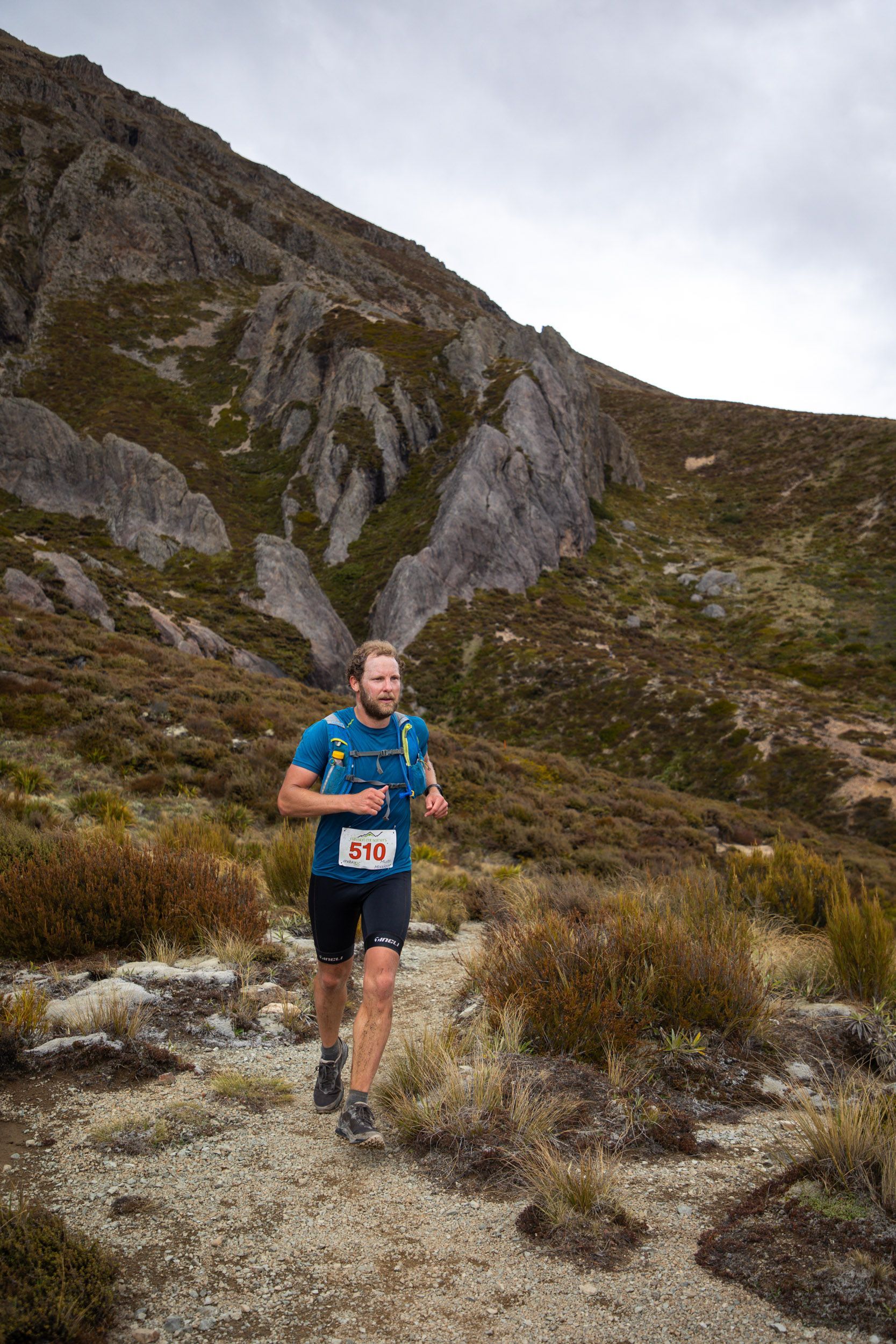 A man is running on a trail in the mountains.