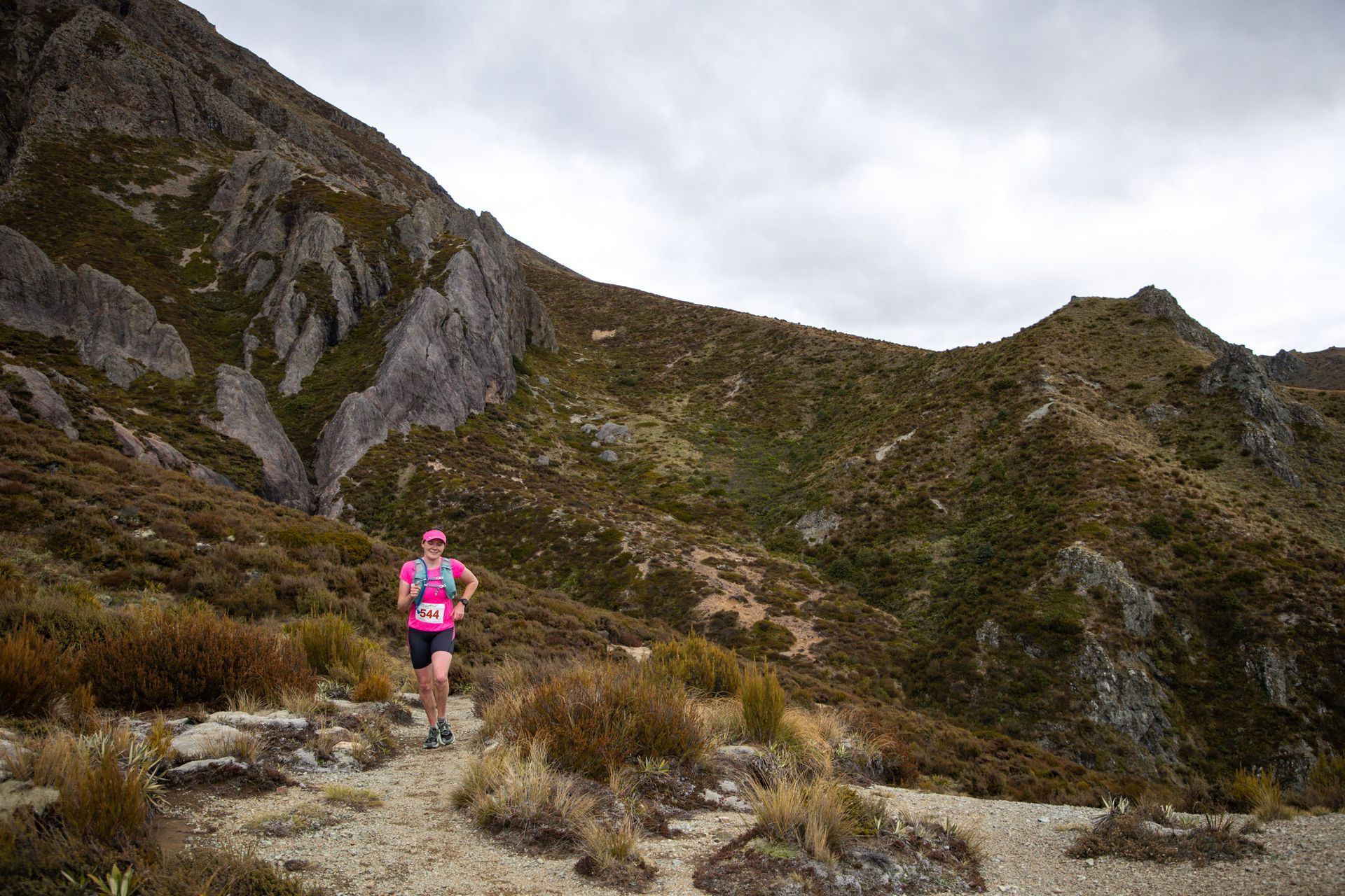 A woman is running on a trail in the mountains.