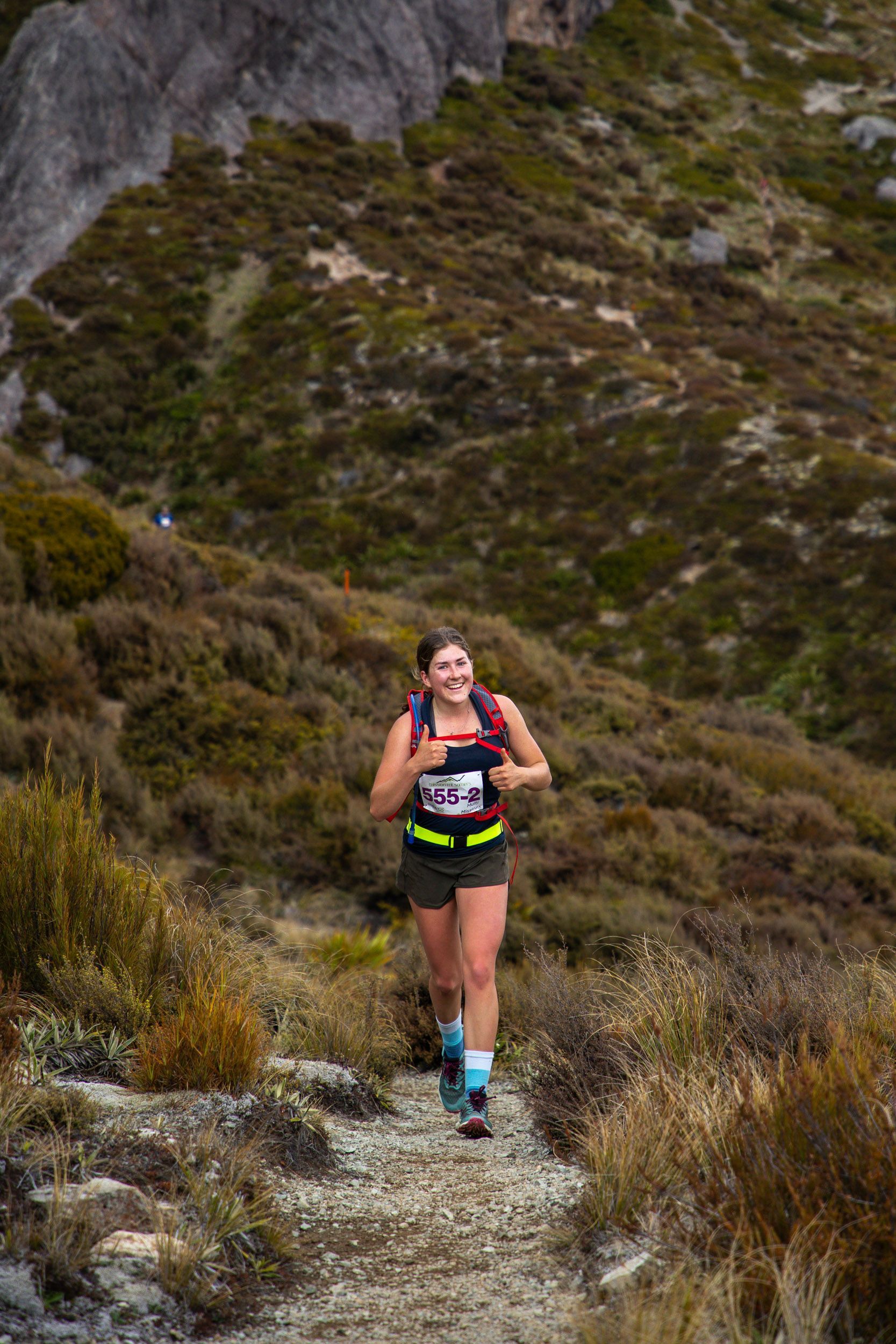 A woman is running on a trail in the mountains.