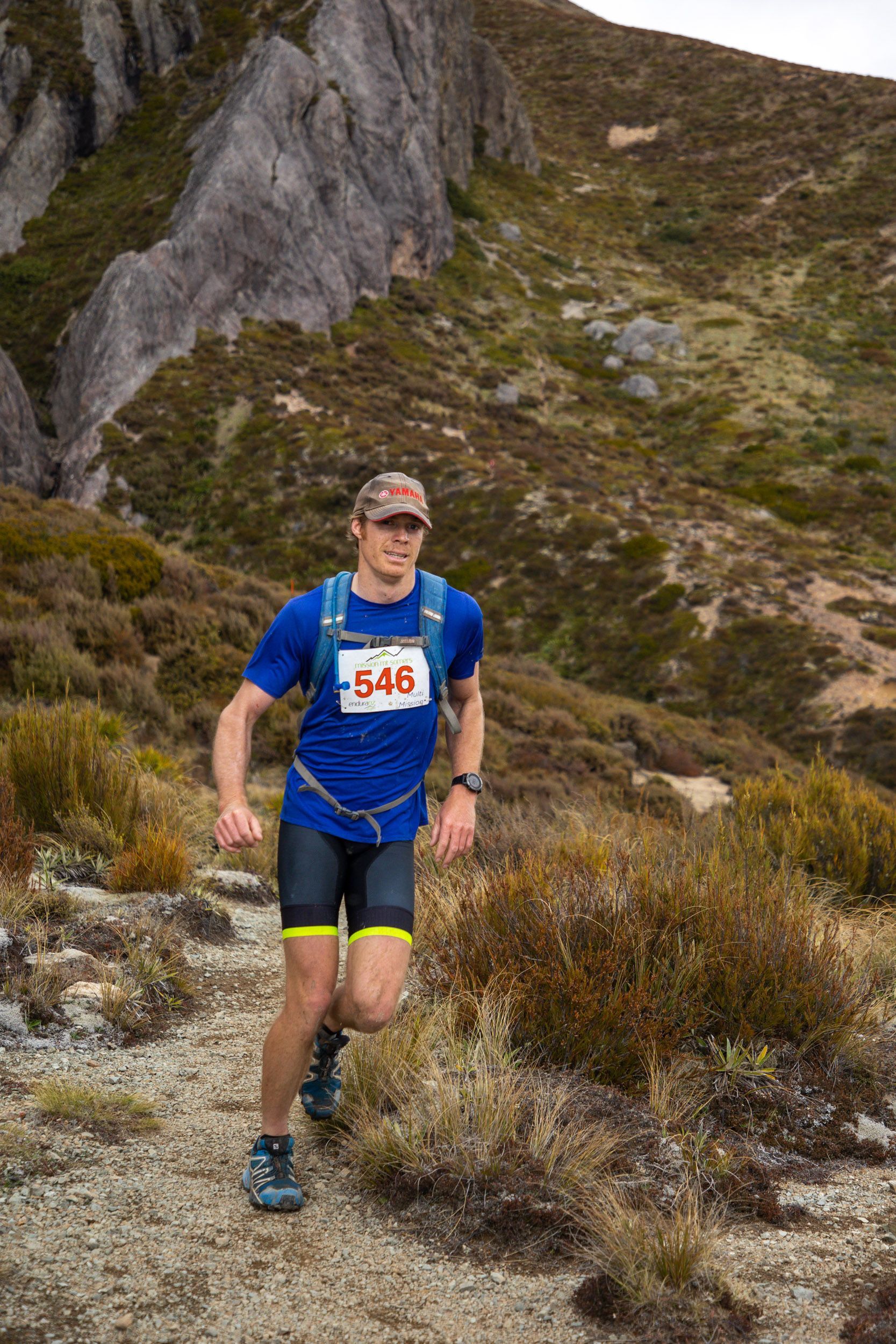 A man is running on a trail in the mountains.