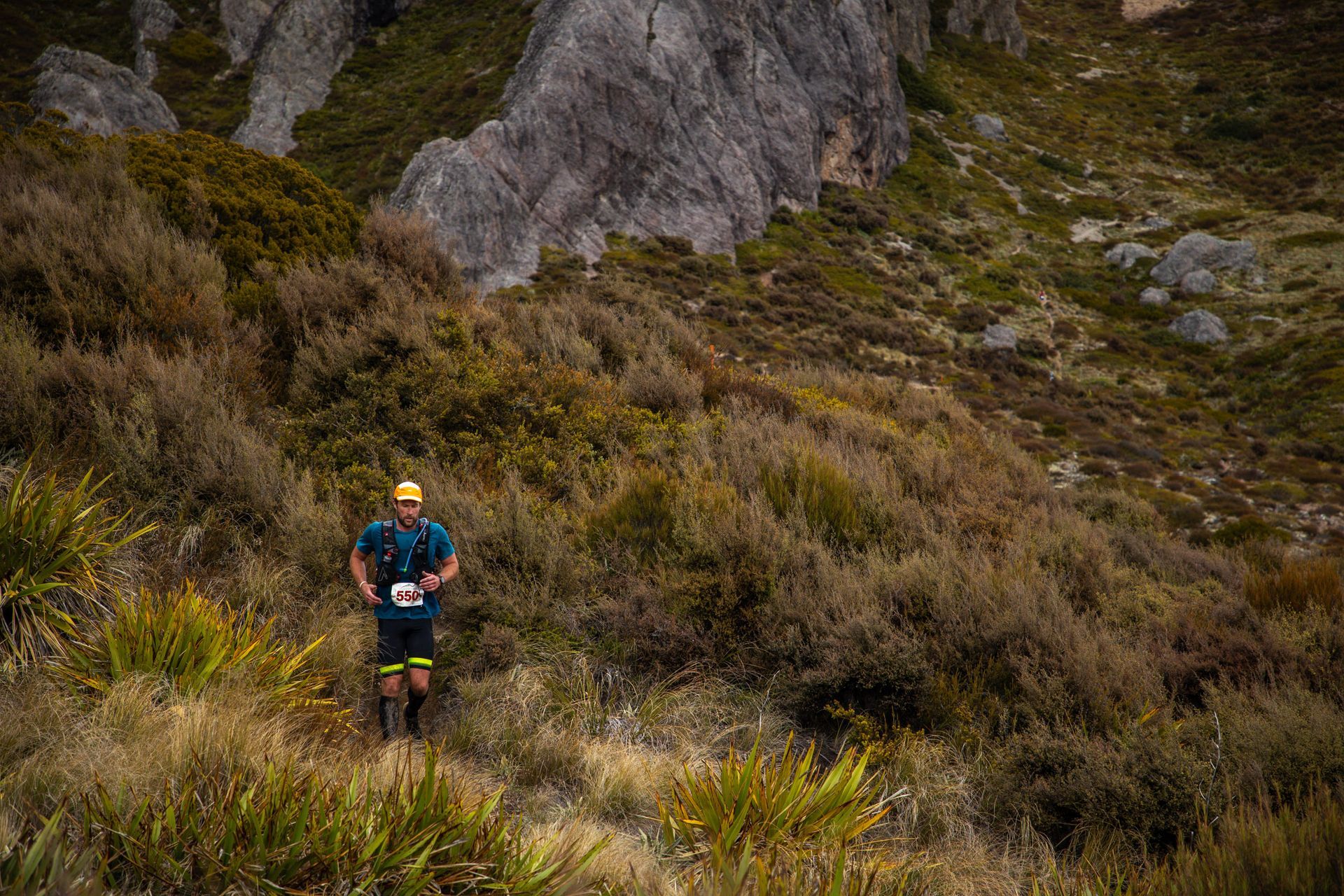 A man is running on a trail in the mountains.