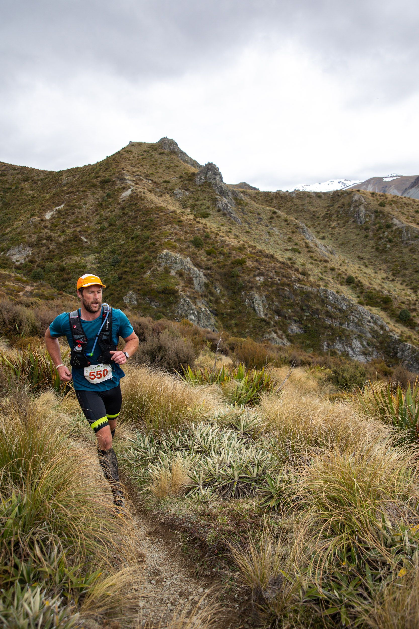 A man is running on a trail in the mountains.