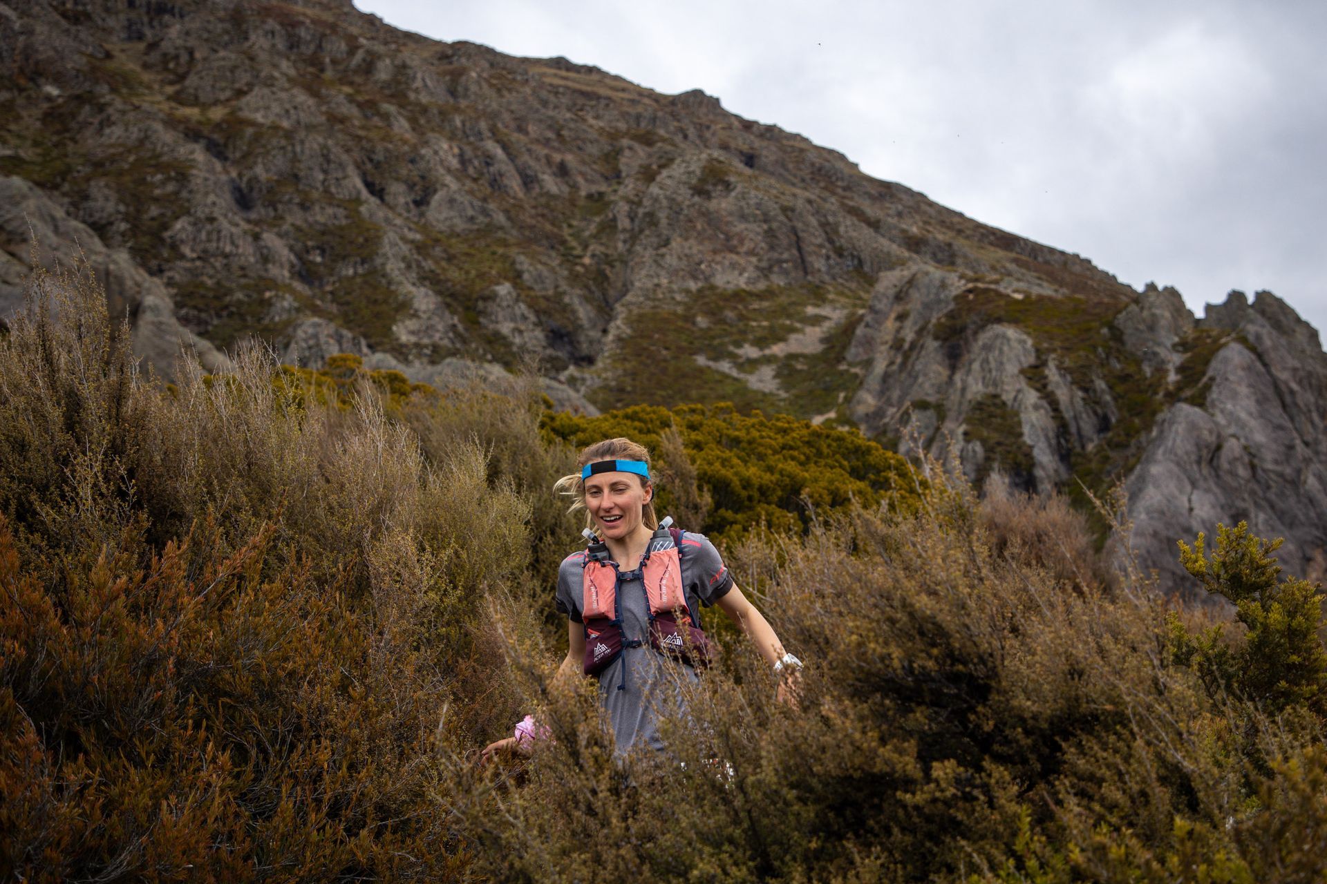 A woman is running up a hill in the mountains.