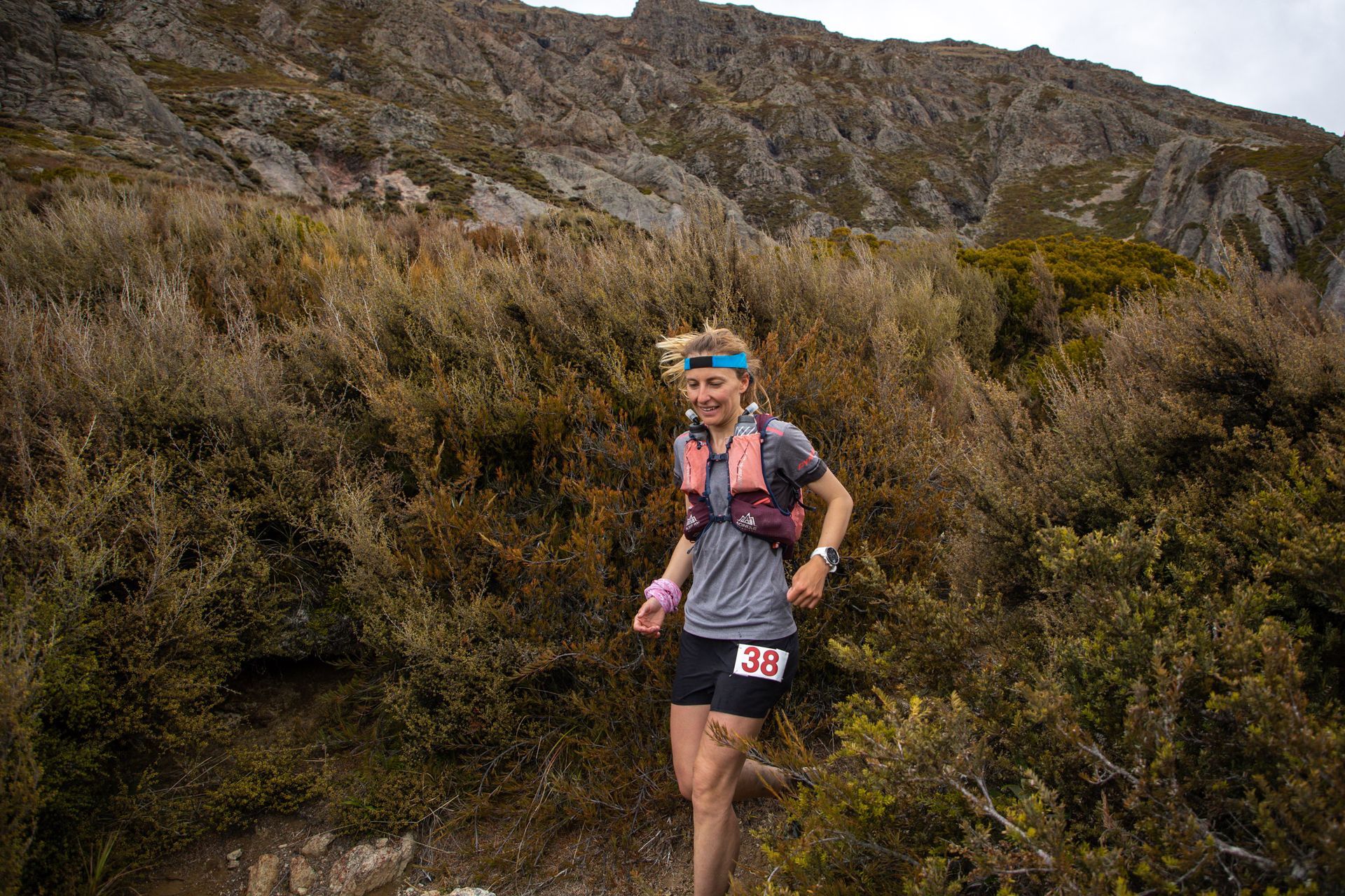 A woman is running on a trail in the mountains.