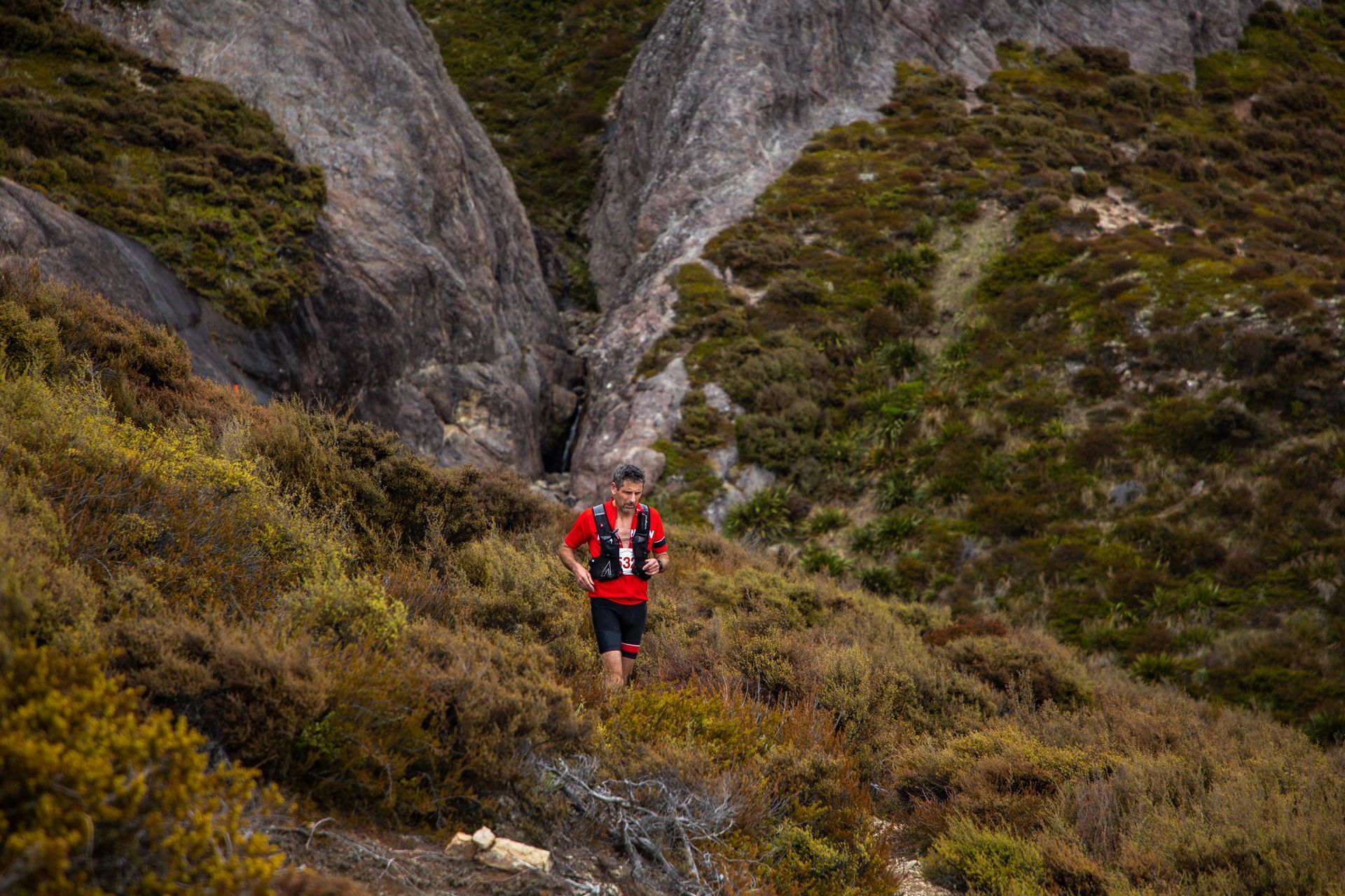 A man is running on a trail in the mountains.