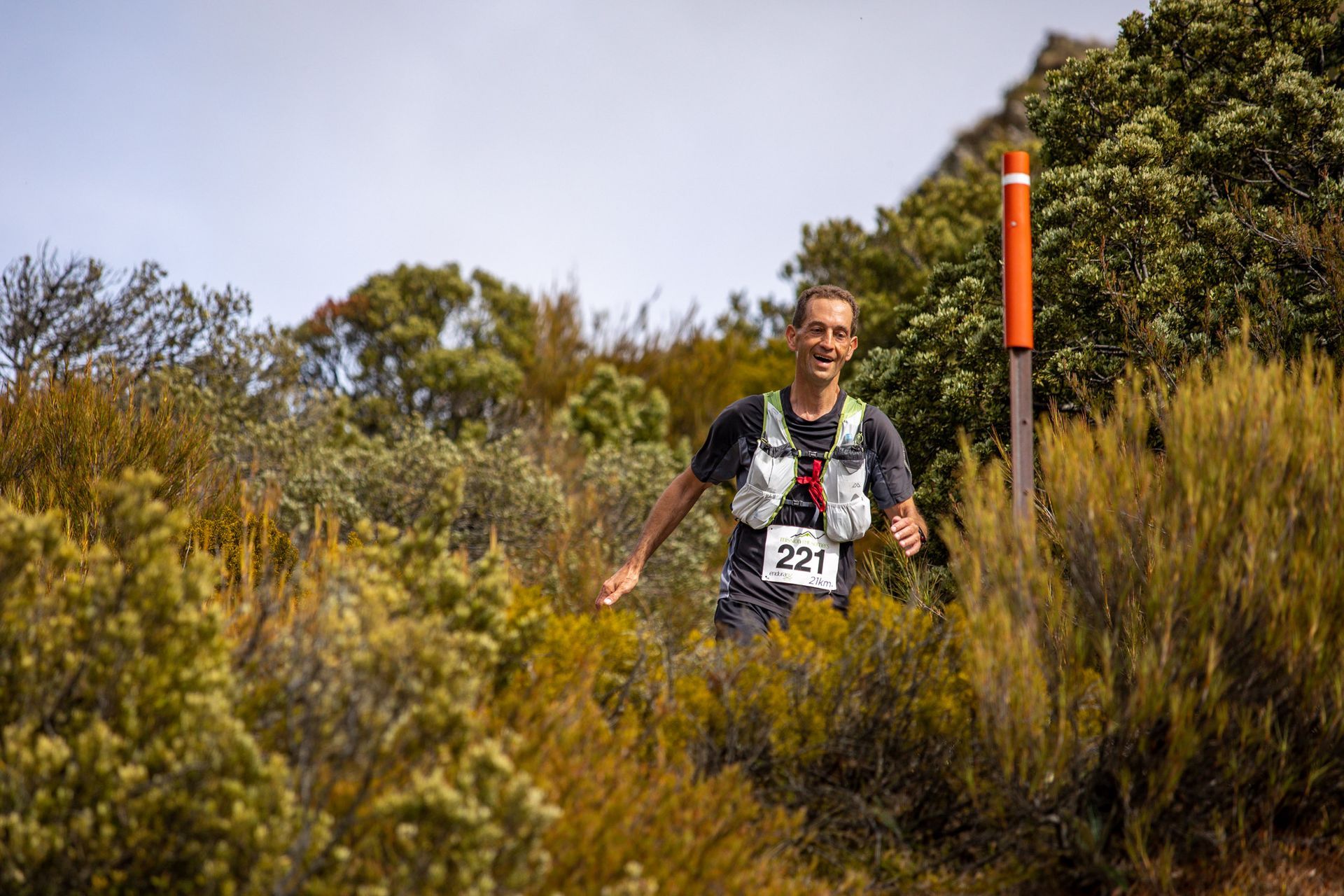 A man is running on a trail in the woods.