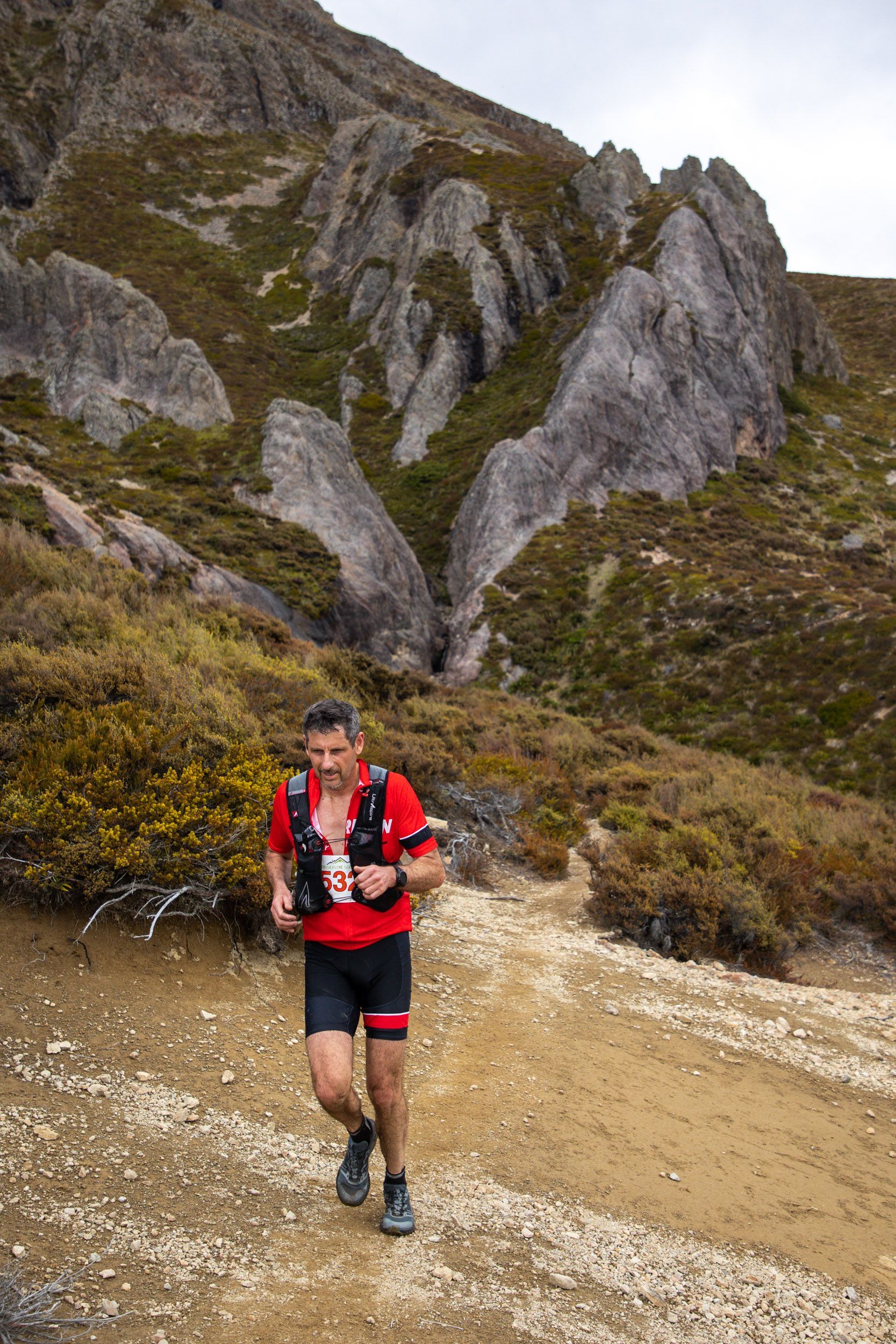 A man is running on a dirt path in the mountains.