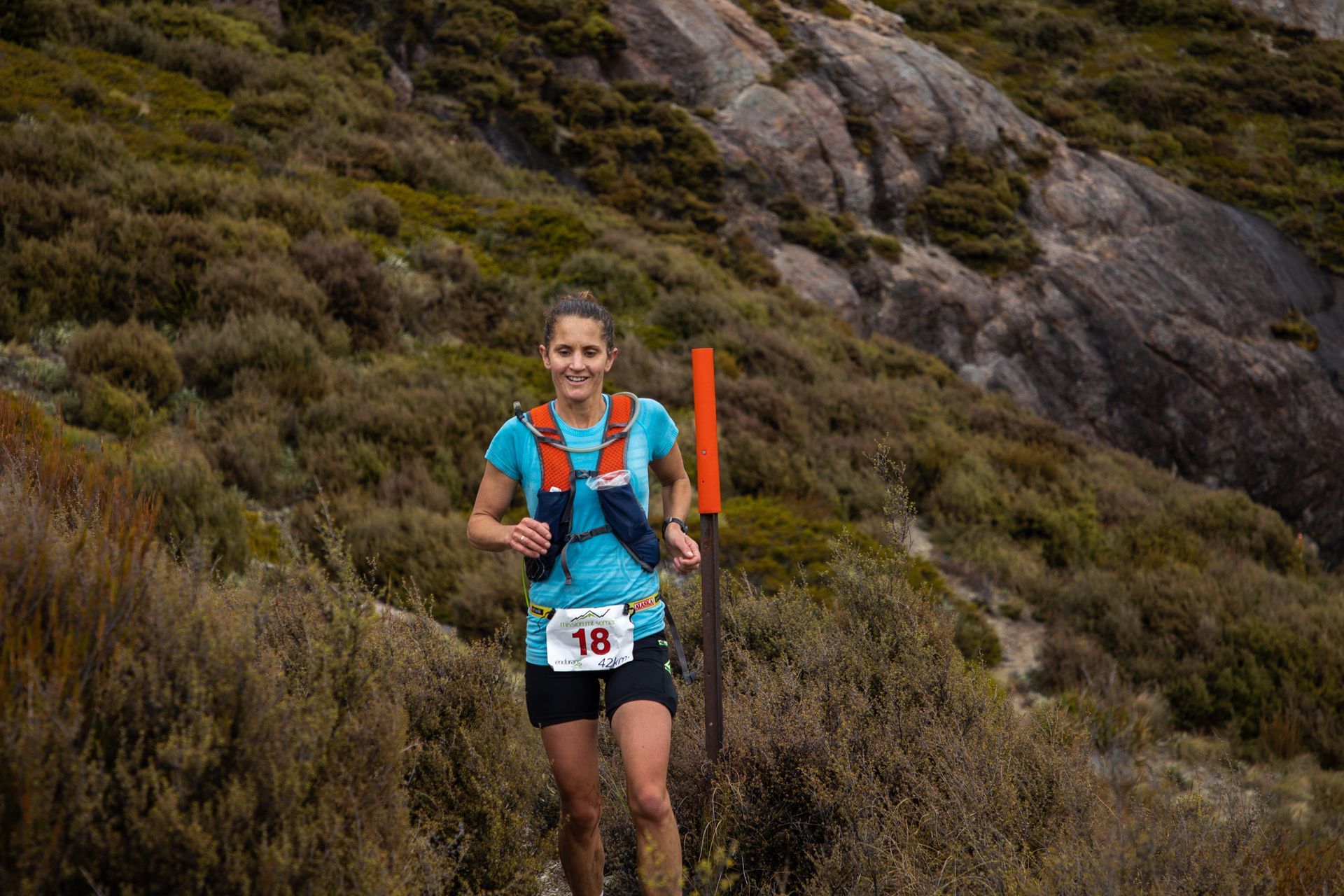 A woman is running on a trail in the mountains.