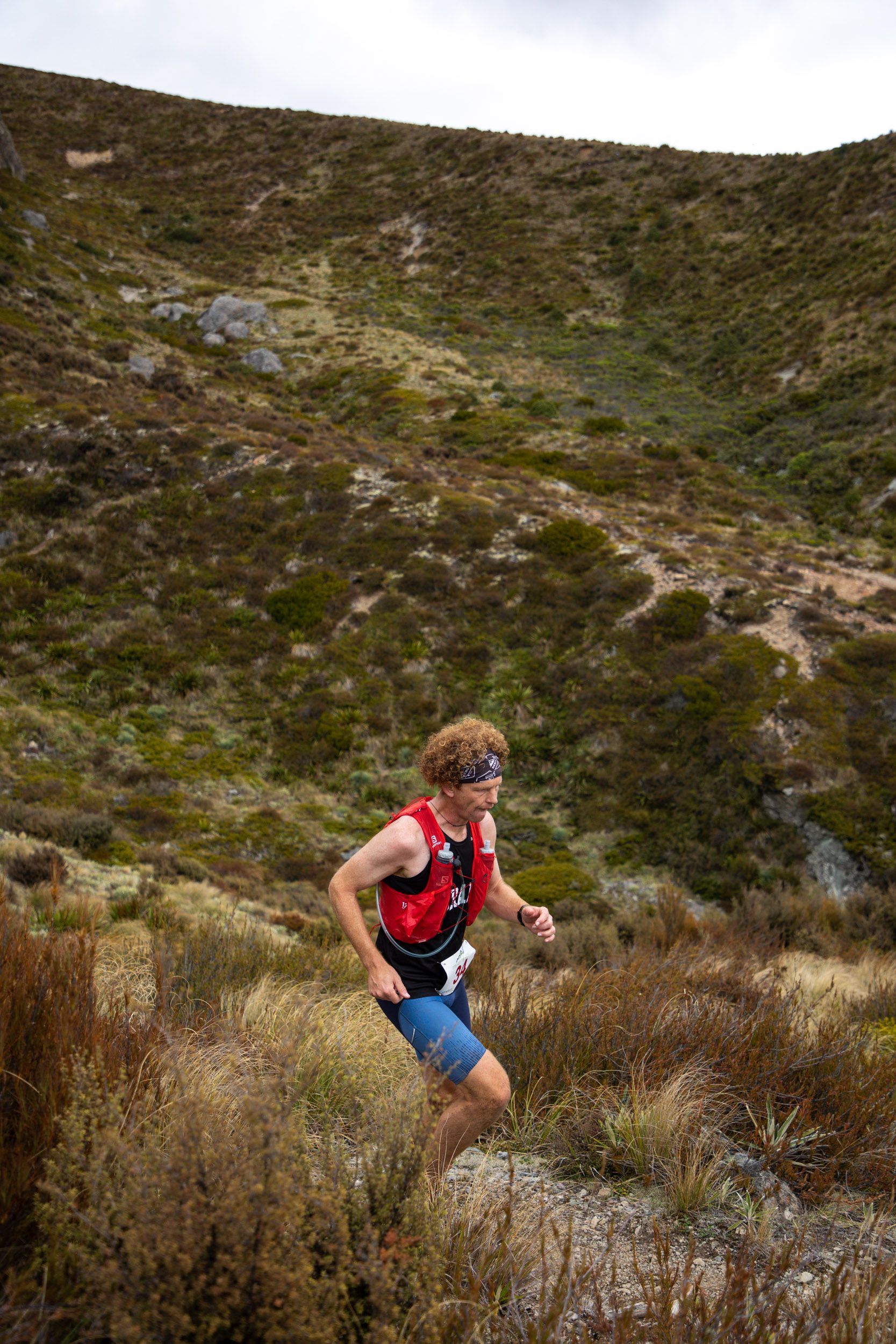 A man is running up a hill on a trail.