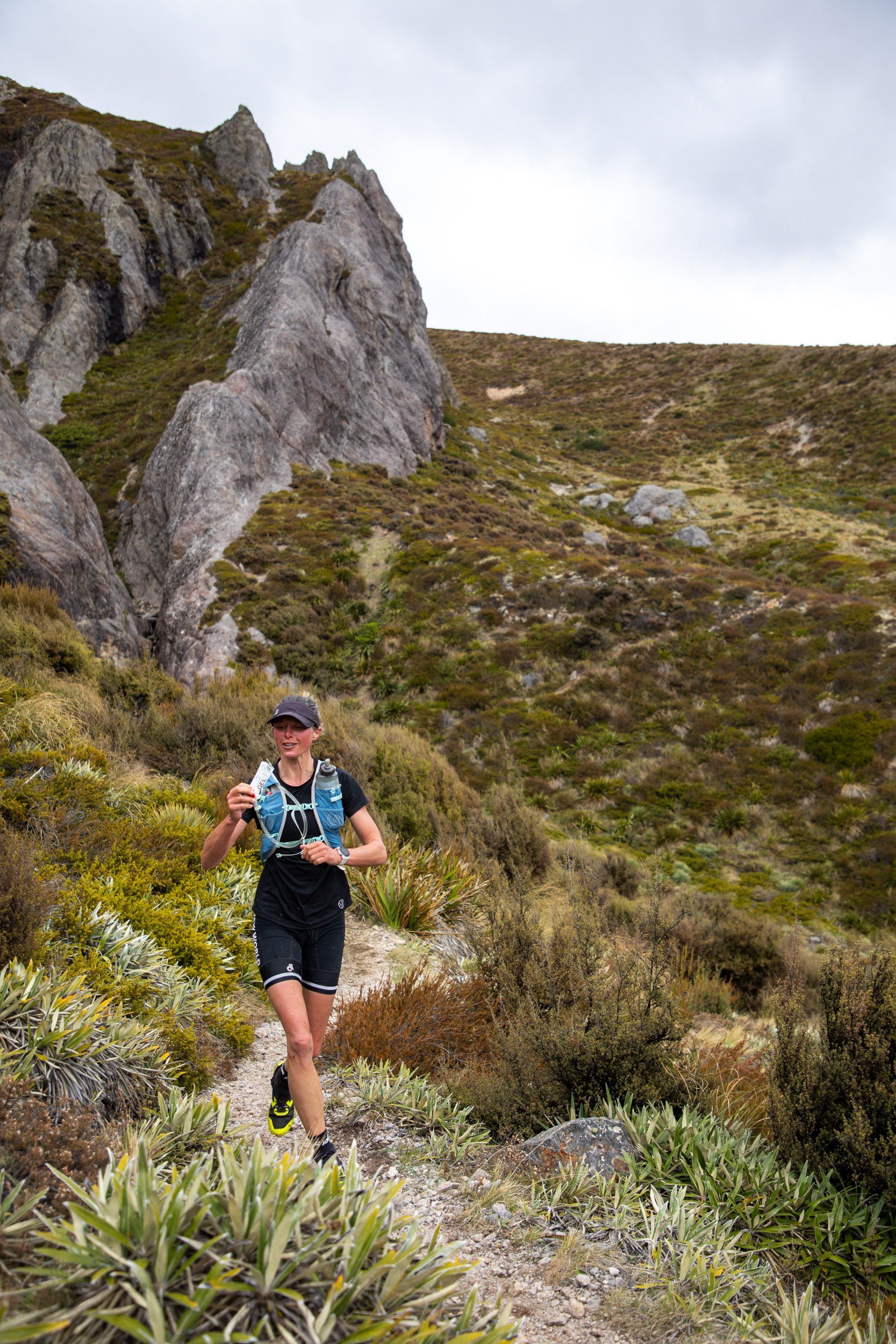 A woman is running on a trail in the mountains.