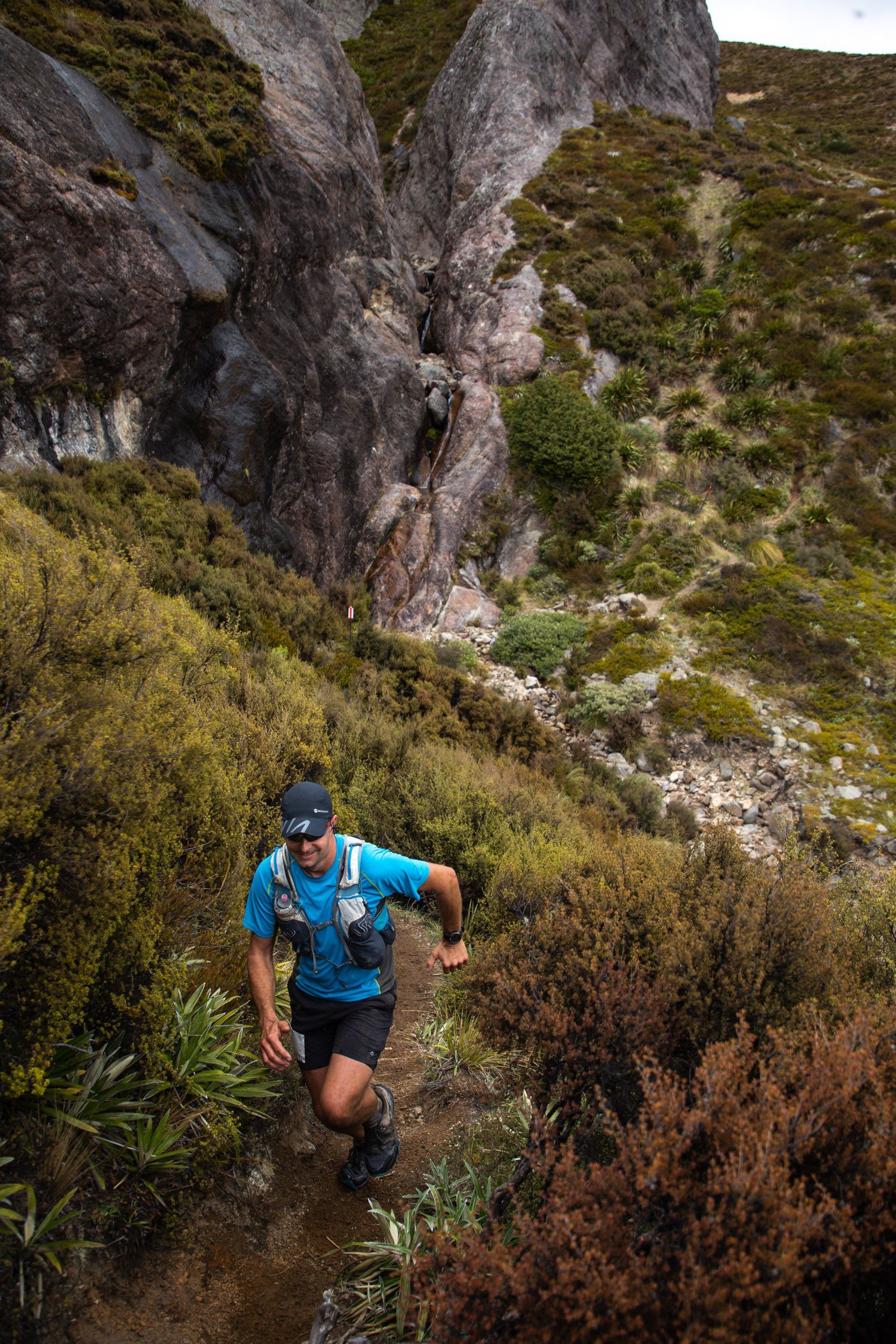 A man is running down a trail in the woods.