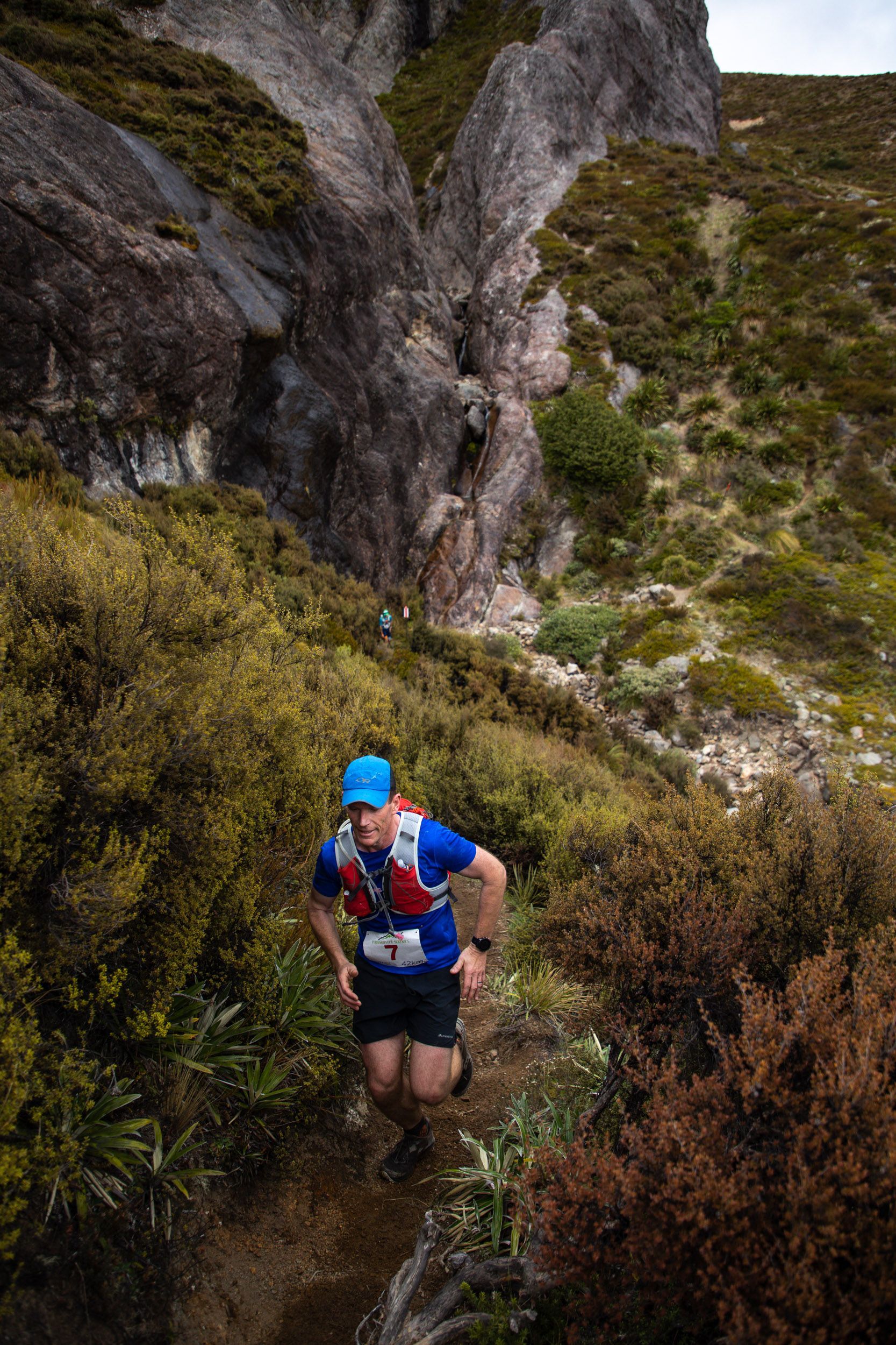 A man is running up a hill in the woods.