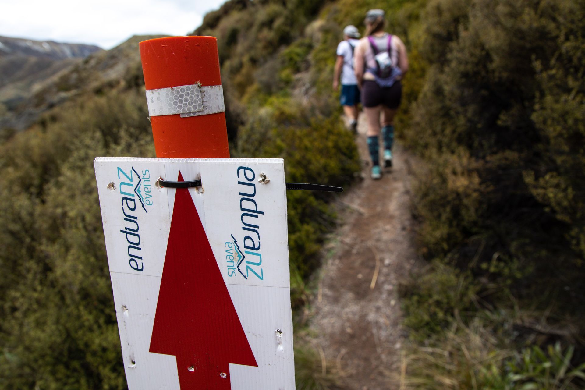 Two people are walking down a trail next to a sign that says enduro