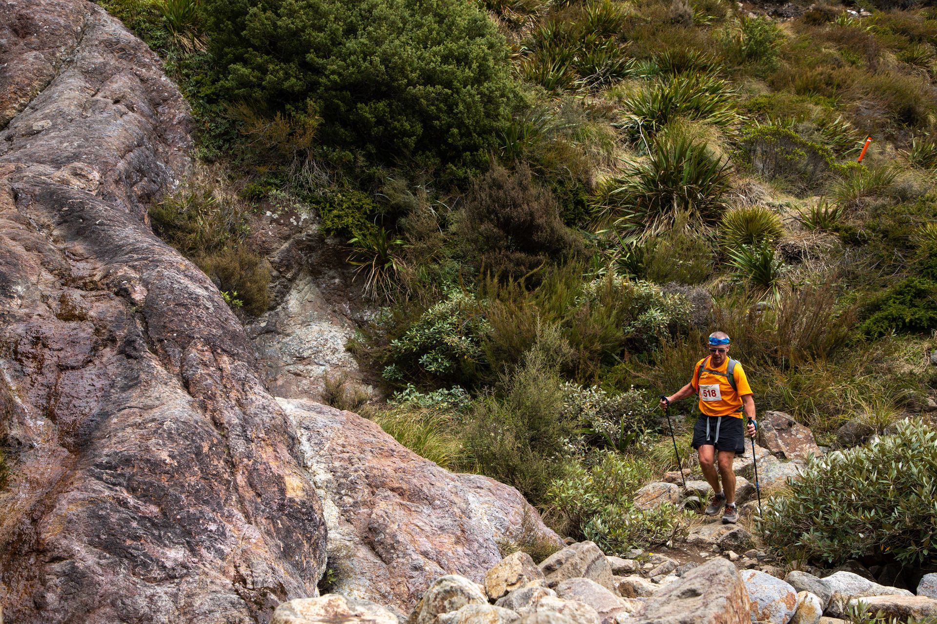 A man is walking down a rocky trail in the woods.